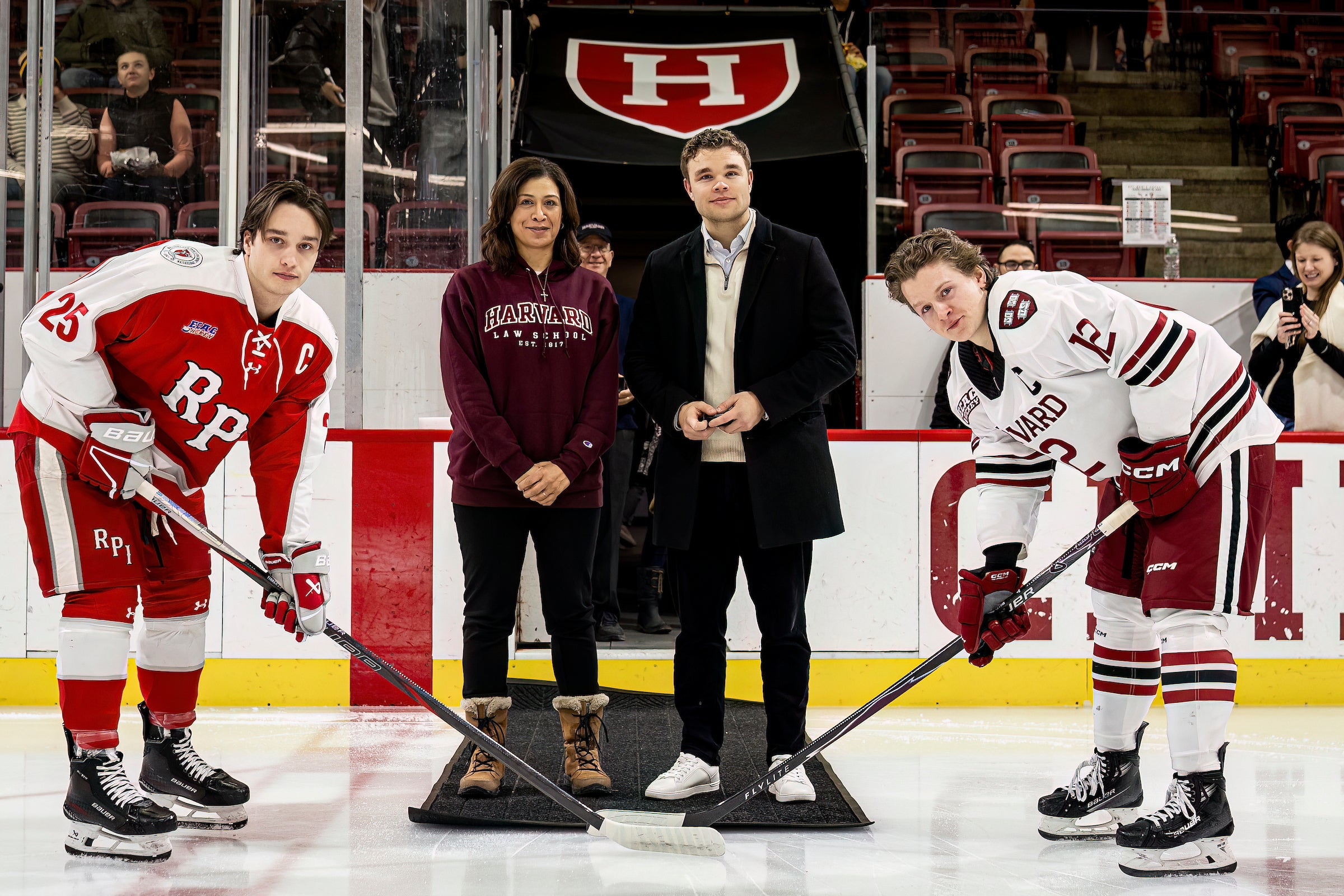 Two hockey players and two people pose for a picture before a puck drop.