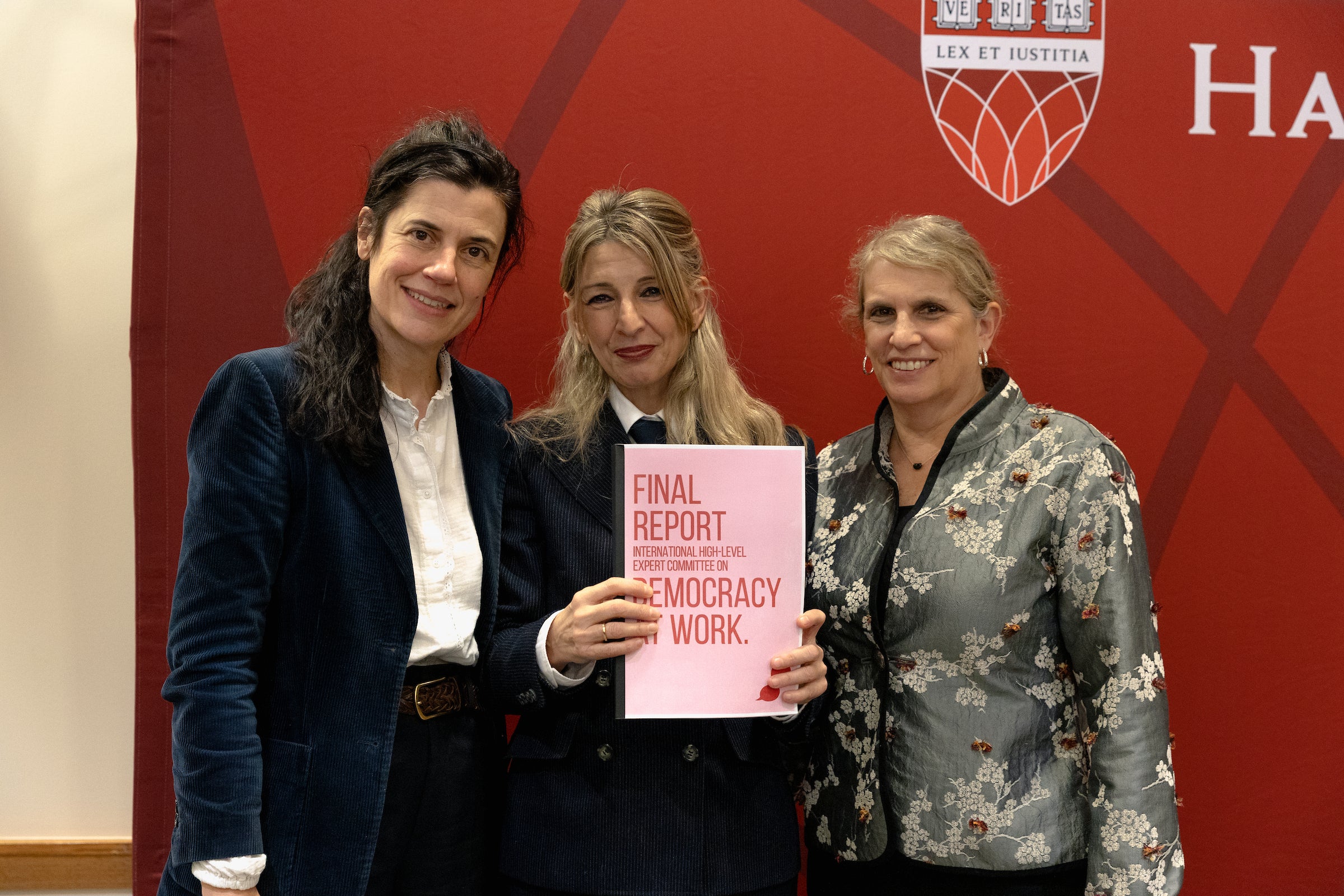 Three women pose for a photo with an award plaque.