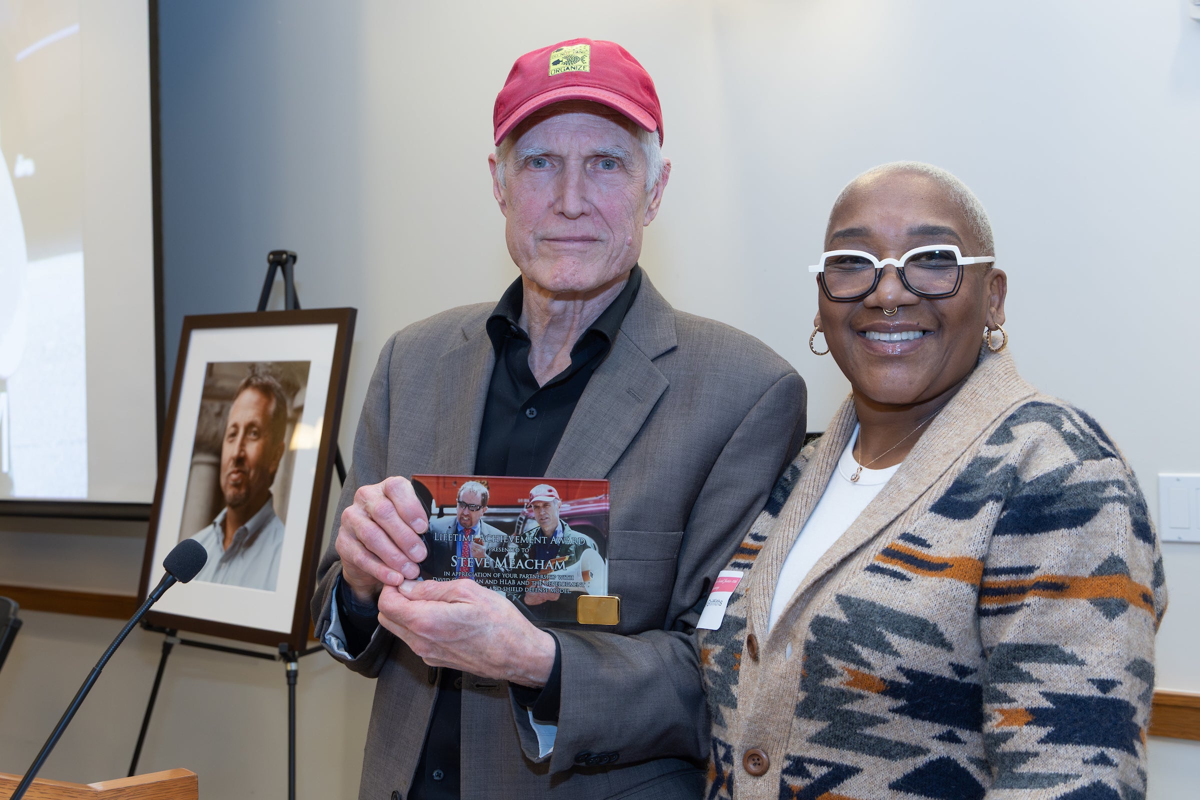 Two people pose for a photo with an award.