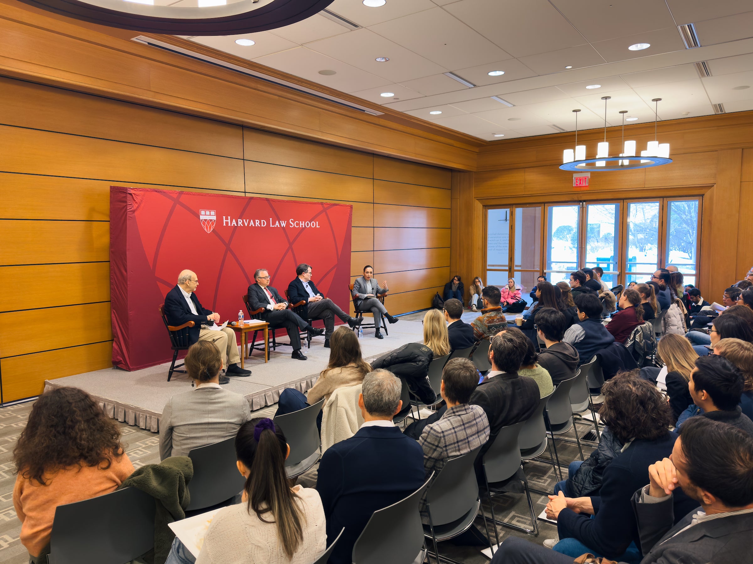 Four people sit on a stage and speak to an audience.