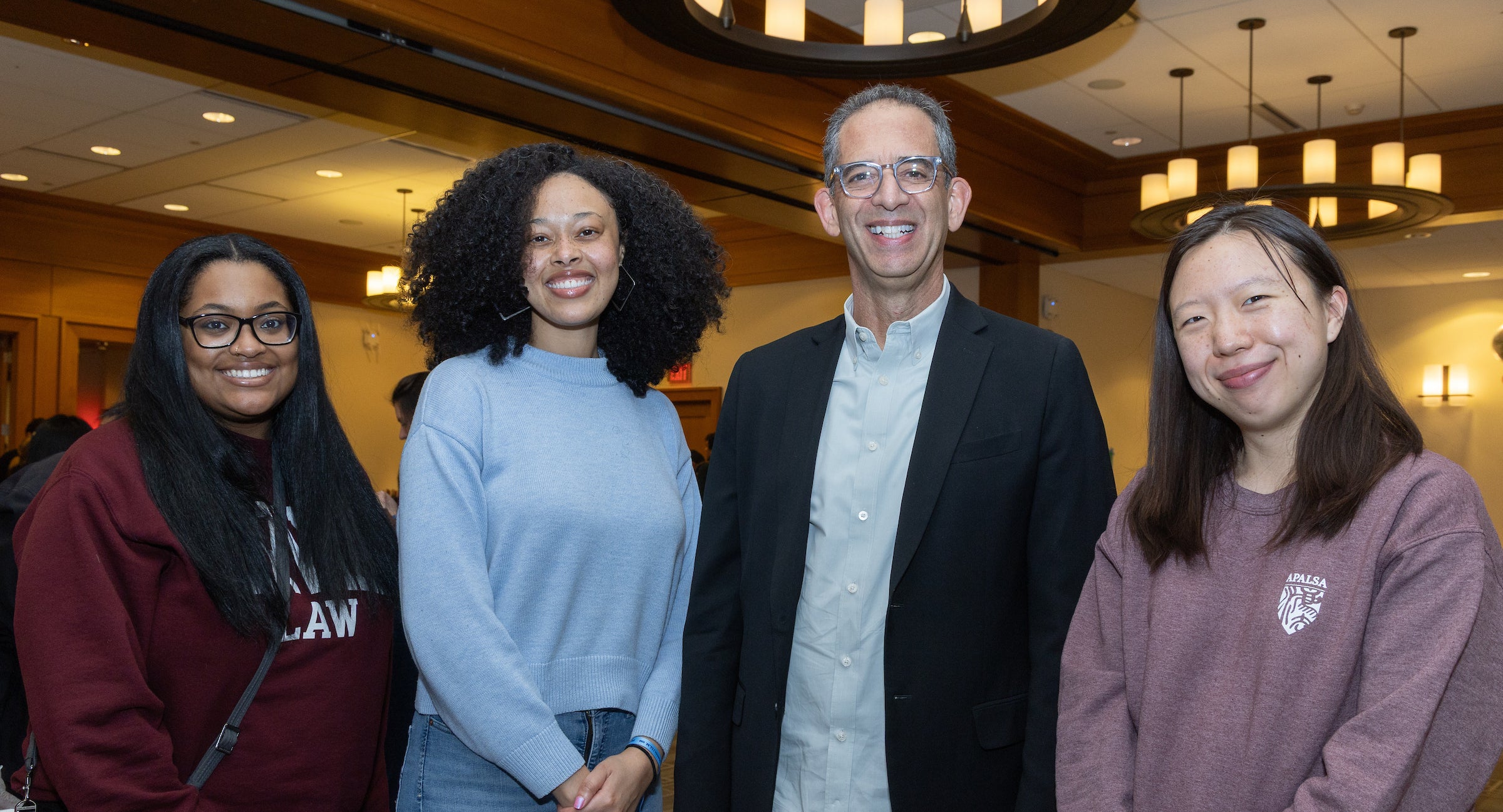 Dean Goldberg poses with three students for a photo.