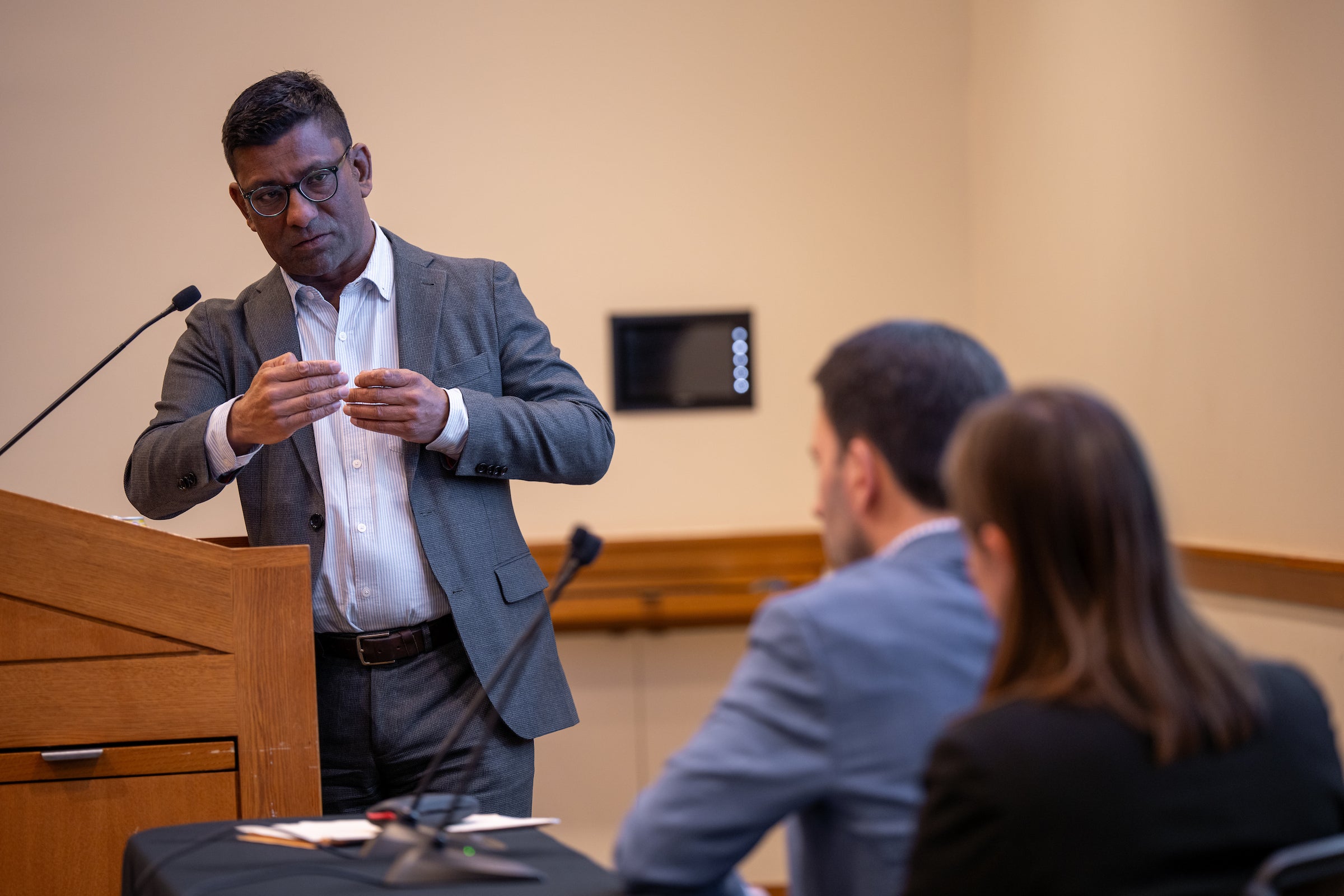 Aziz Huz speaks to panelists from a podium.