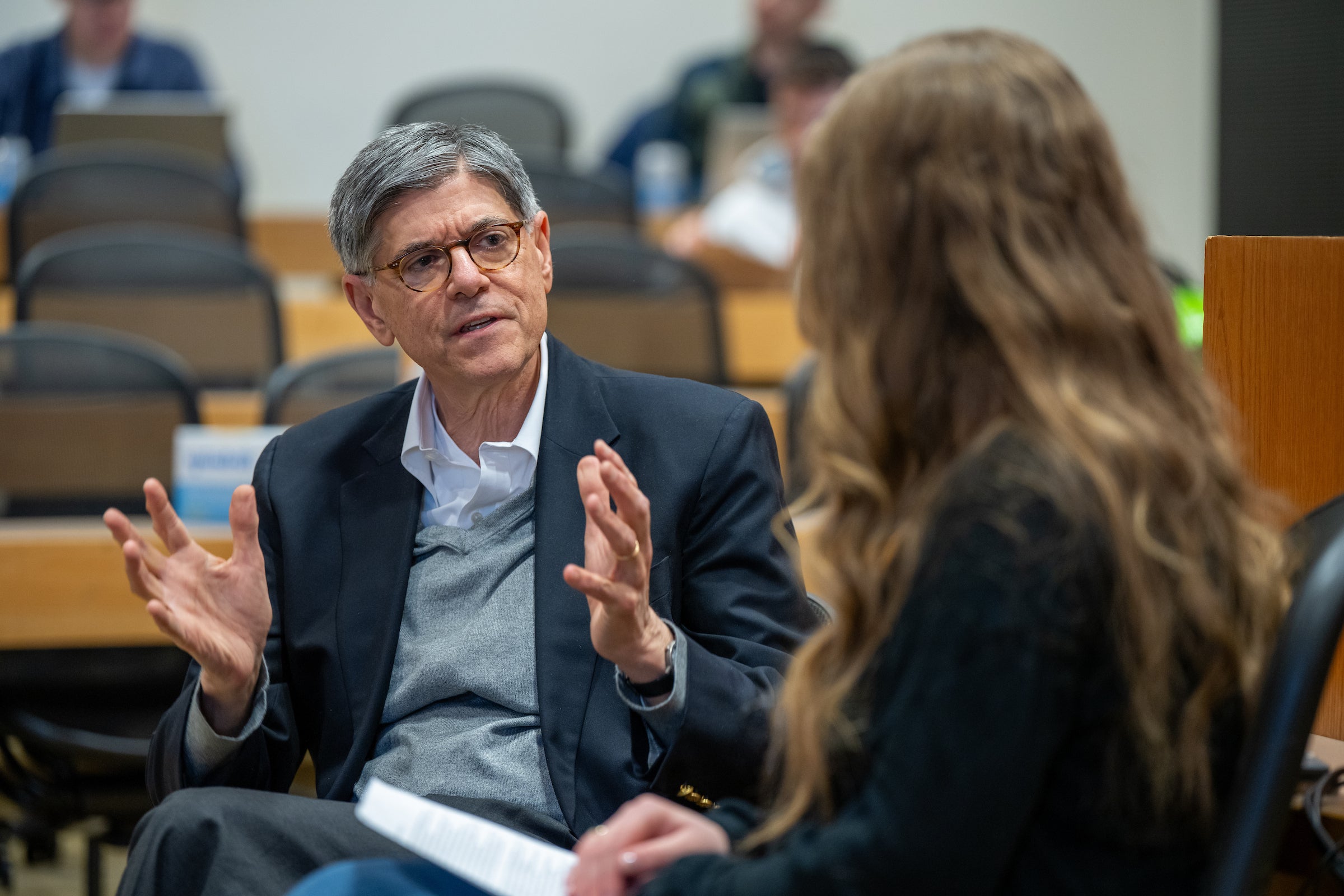 Jack Lew speaks to a moderator in a classroom.