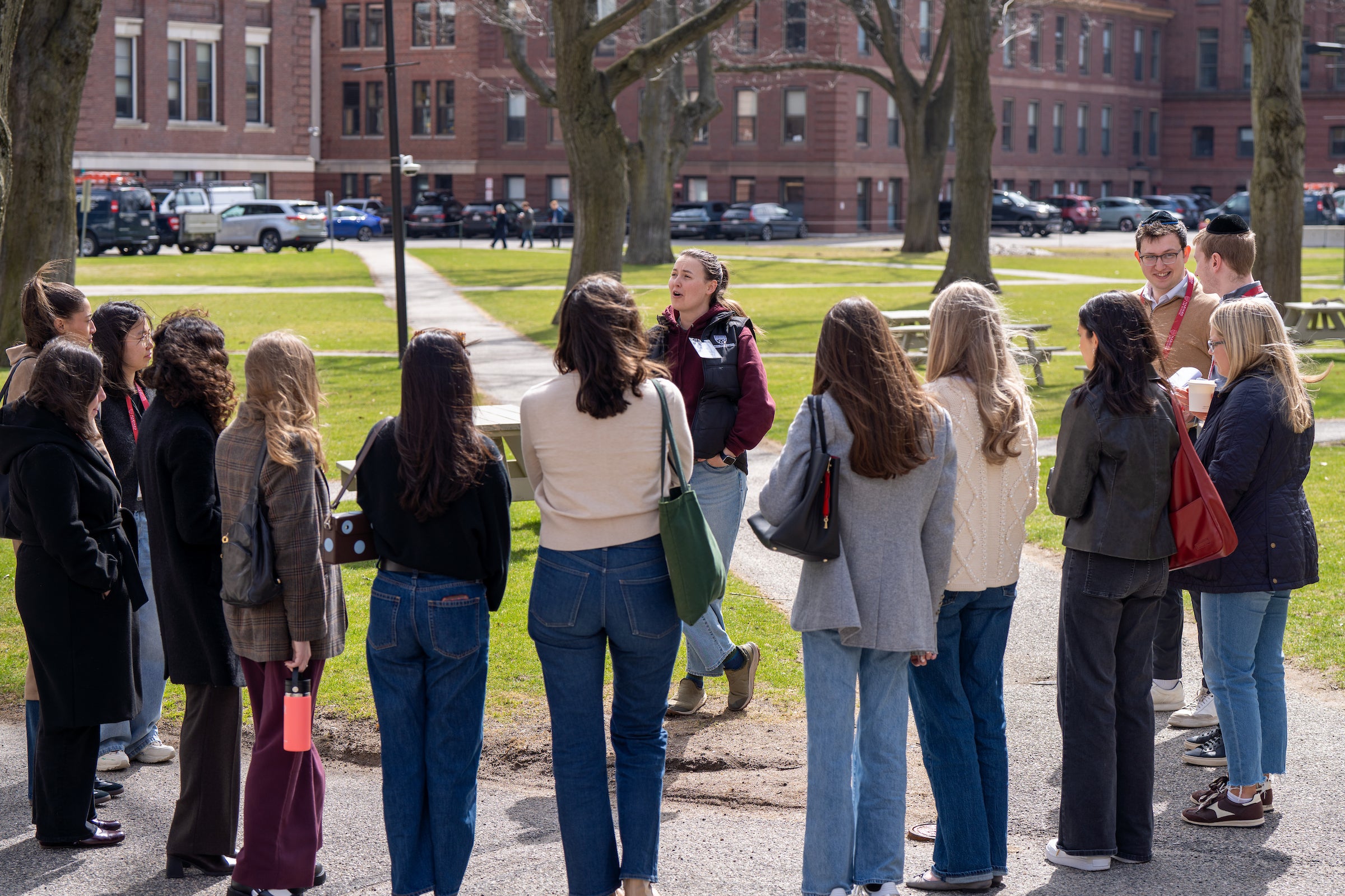 Students surround a speaker on a lawn outside on a campus tour.