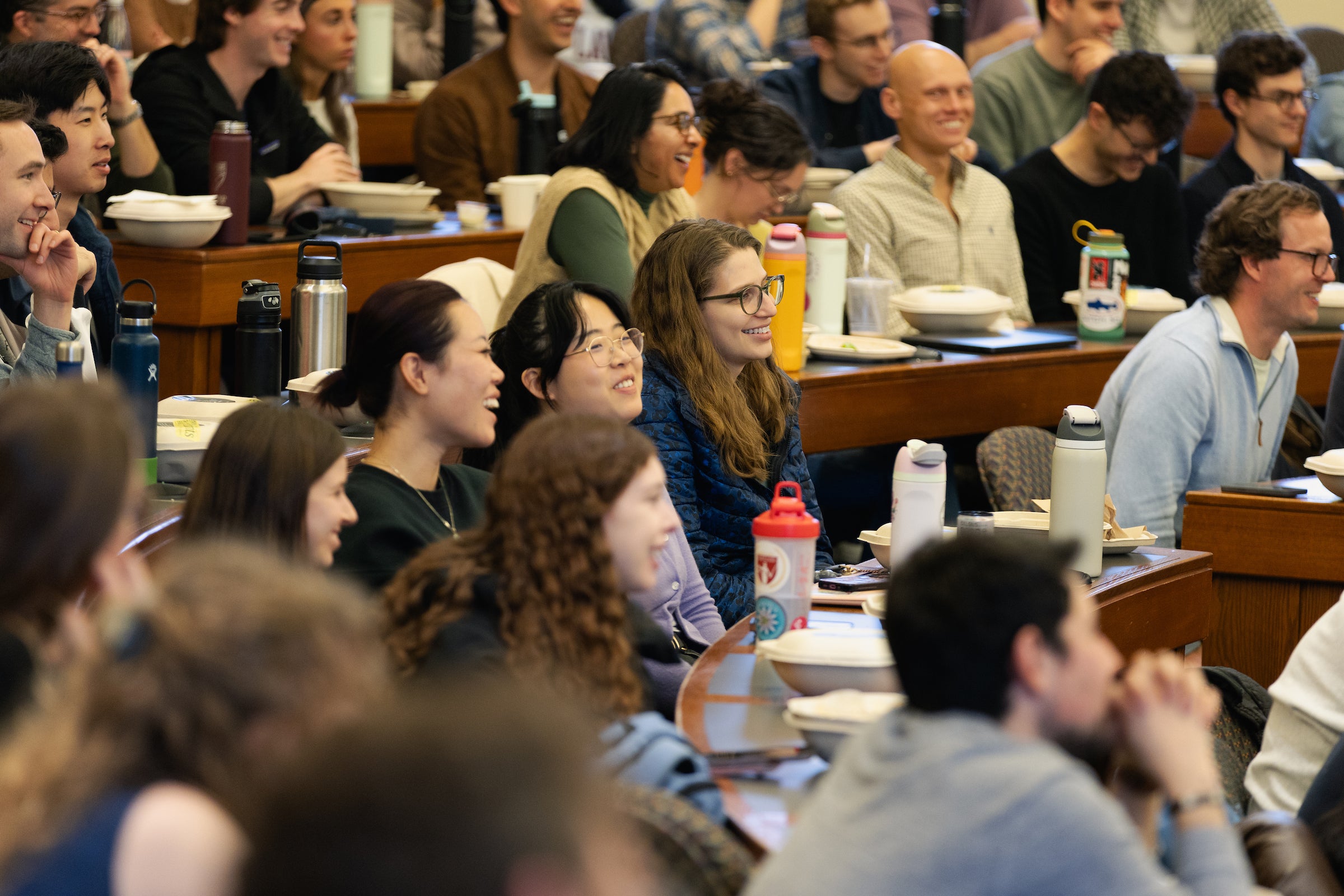 Students in a classroom laugh and listen to a lecture.