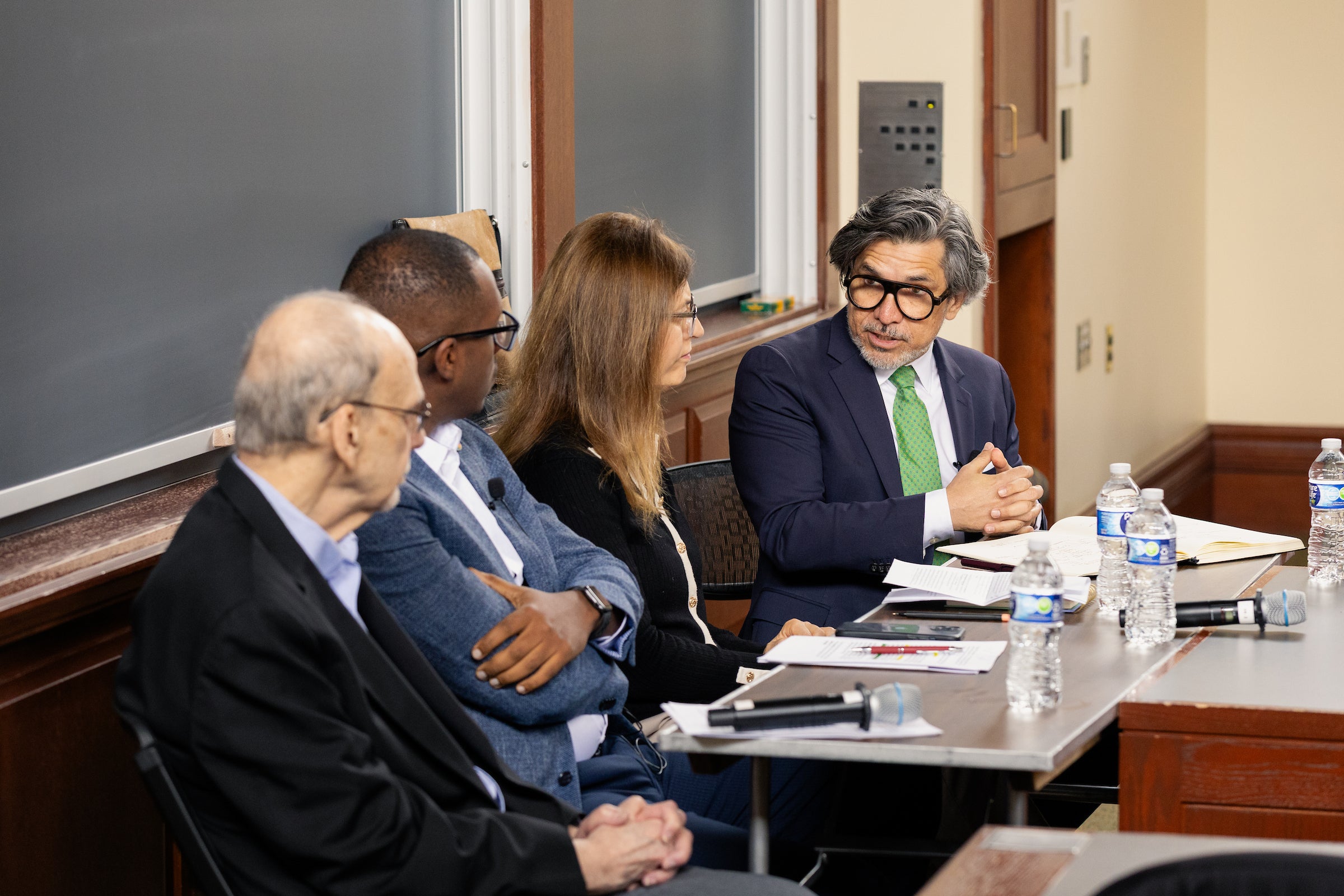 Four people speak on a panel in a classroom.