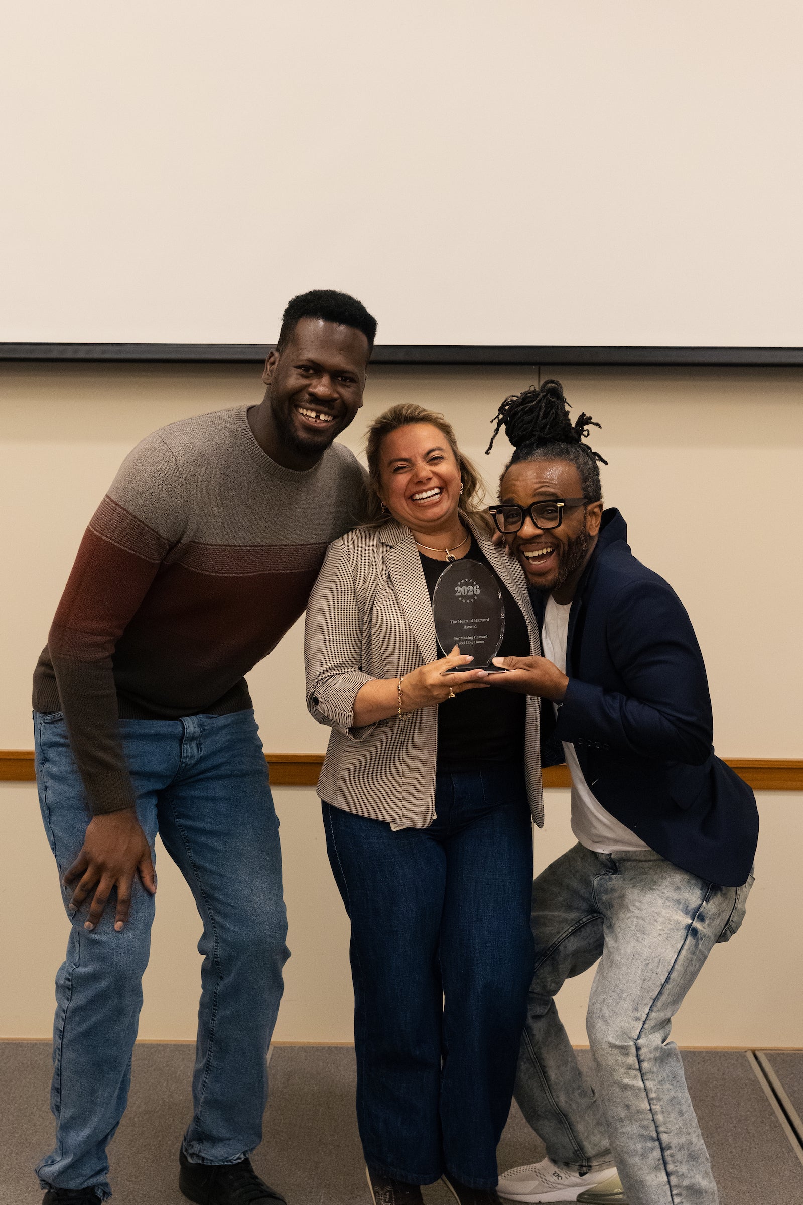 Three people pose together, smiling broadly while holding a 2026 award plaque.
