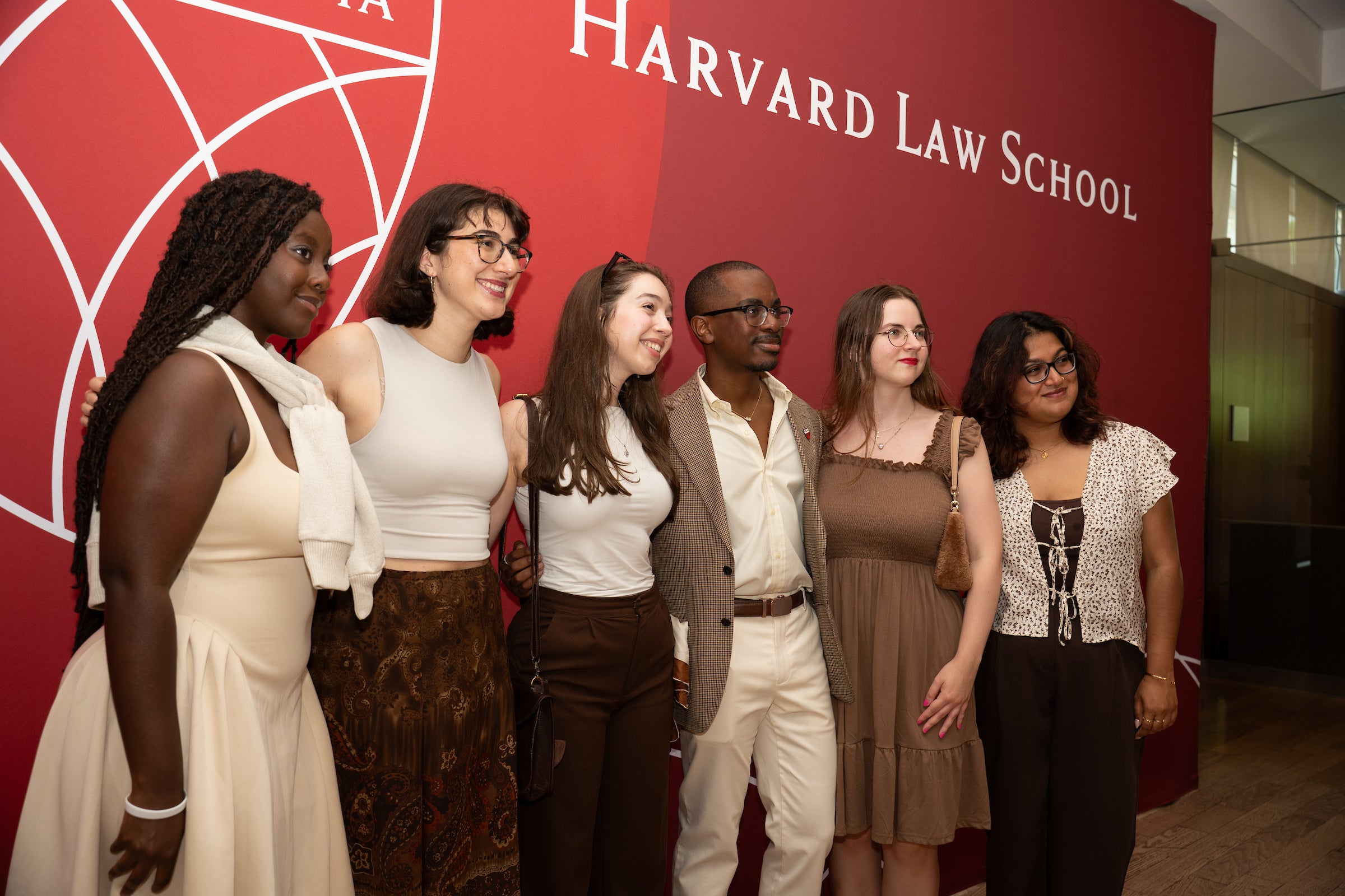 Six individuals pose together in front of a Harvard Law School backdrop.