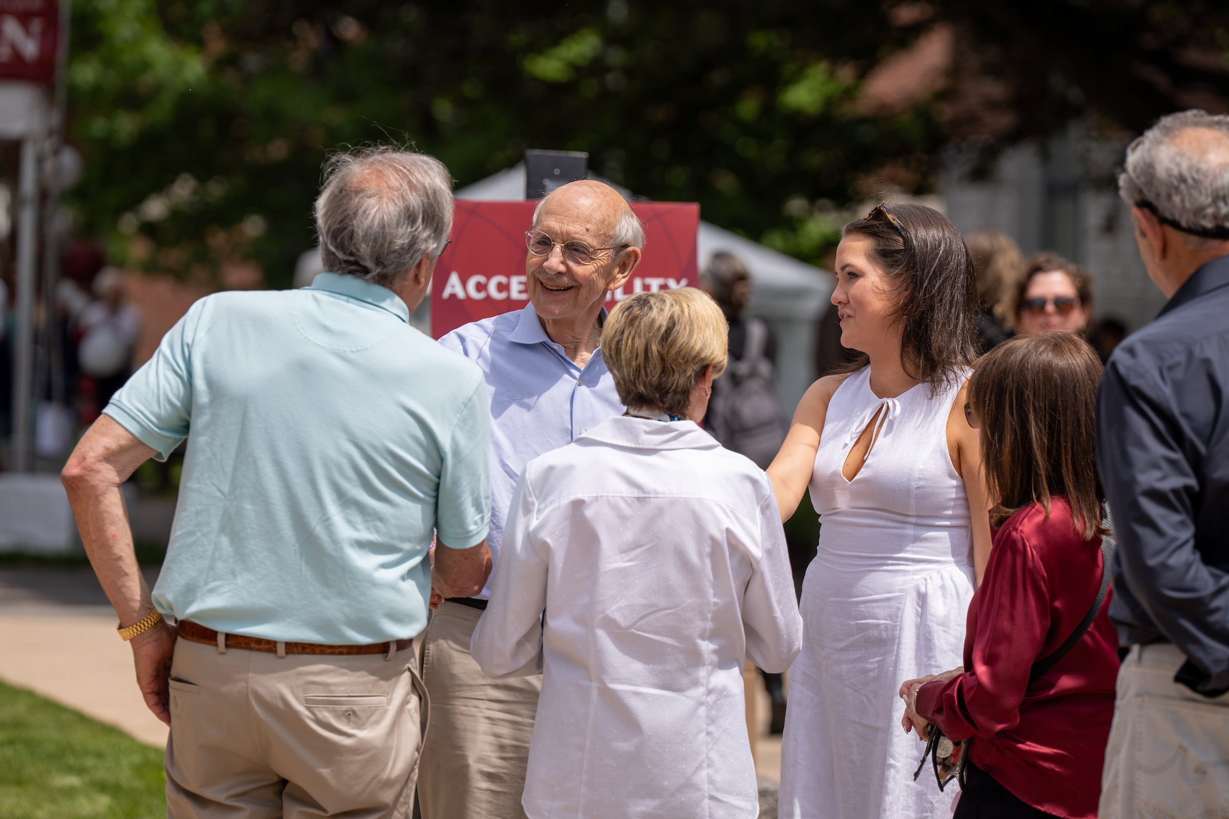 A group of people engage in conversation outdoors.
