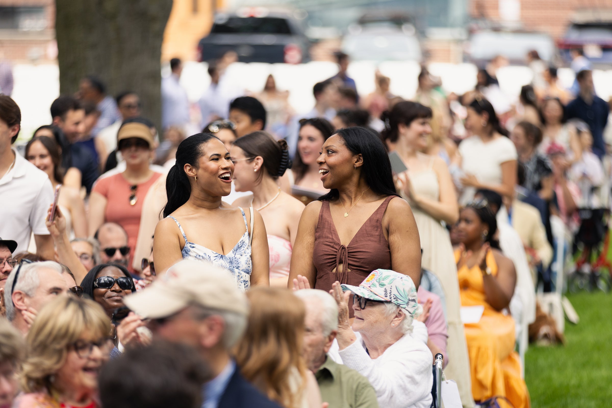 An audience at an outdoor gathering where people are engaged in joyful conversation.