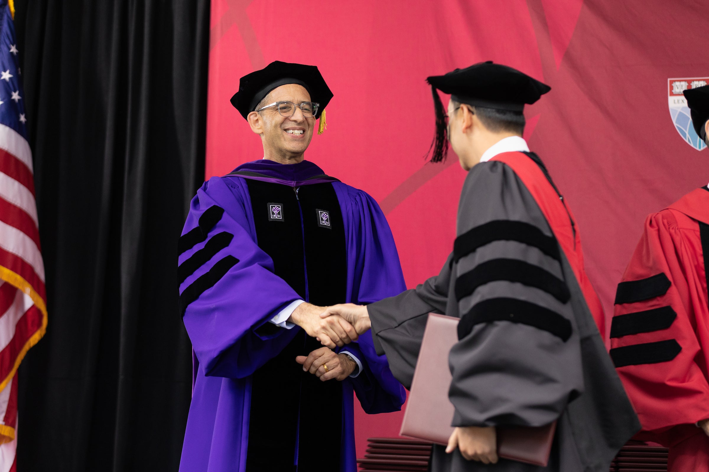 Dean Goldberg shakes a graduate's hand as they accept their diploma.