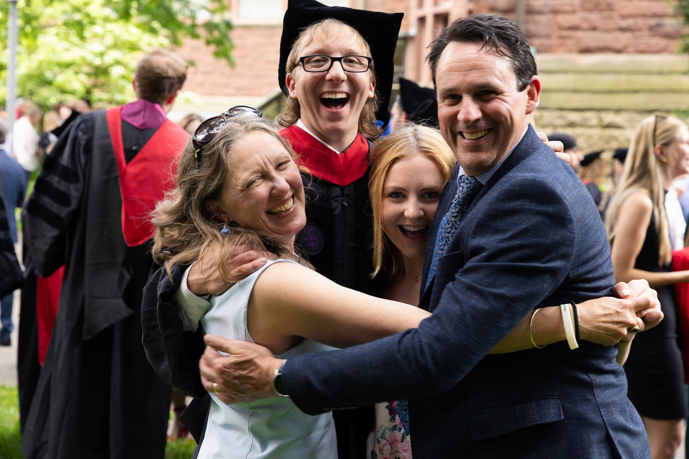 A graduate embraces his family and smiles for a photo.