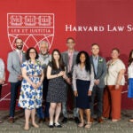 Group posing for photo in front of a Harvard Law School banner.