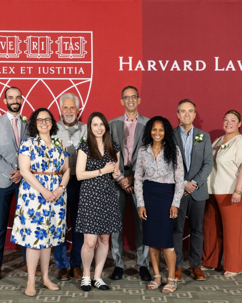 Group posing for photo in front of a Harvard Law School banner.