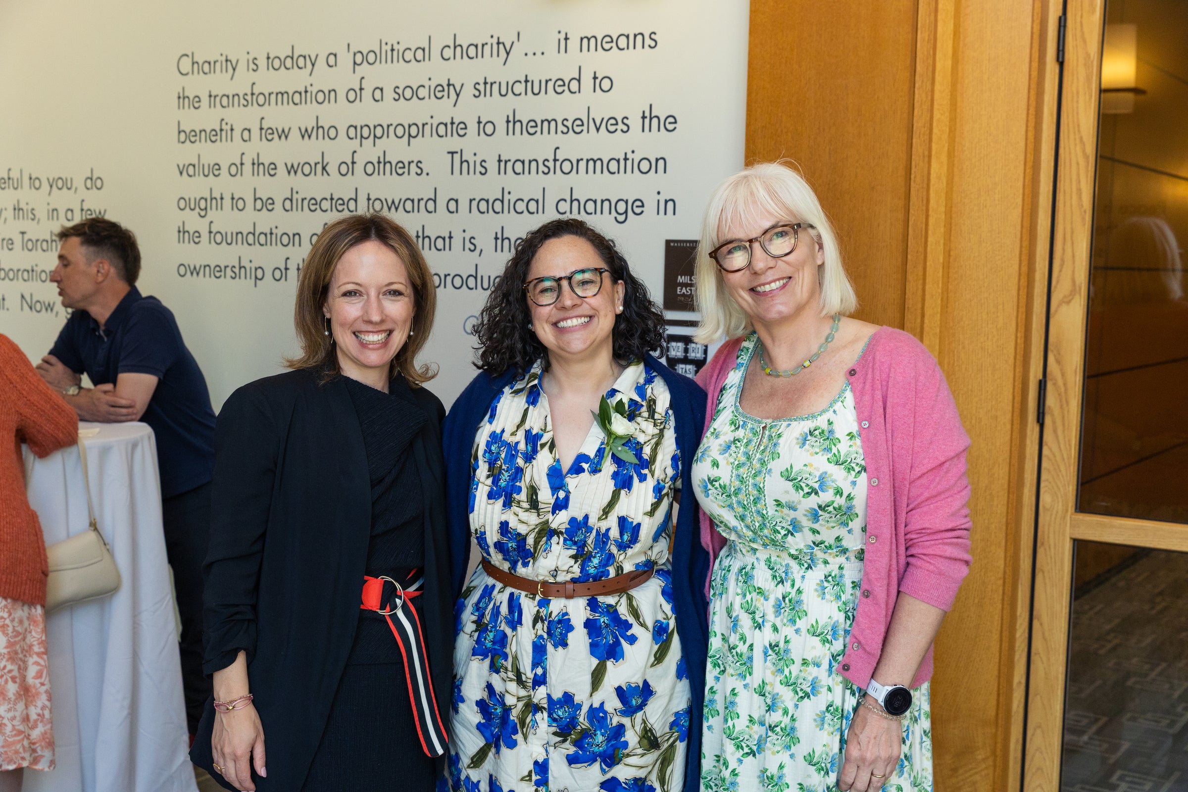 Three individuals pose together and smile for a photo at an event.