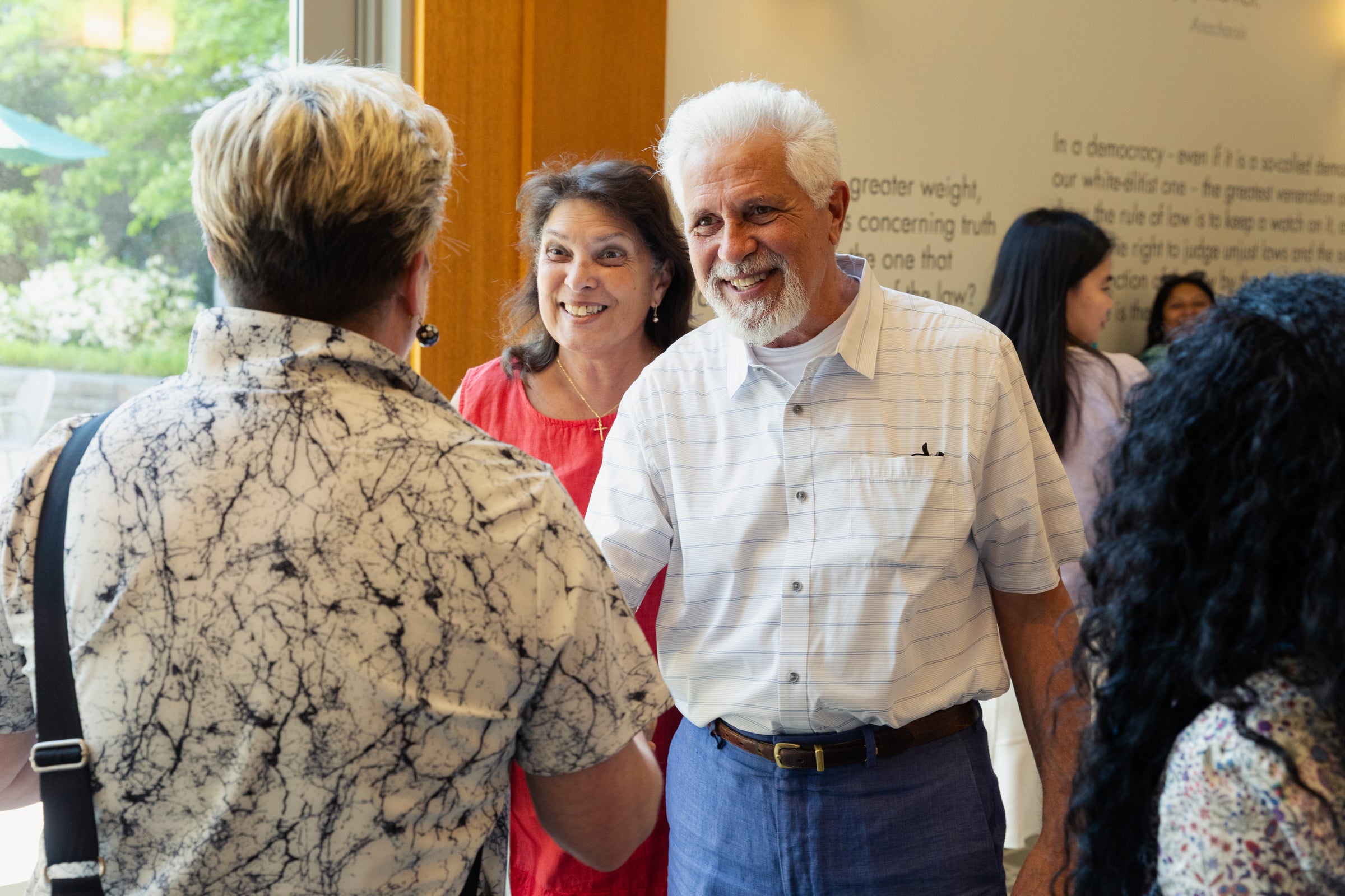 A person smiles while engaging in conversation with others at an indoor event.