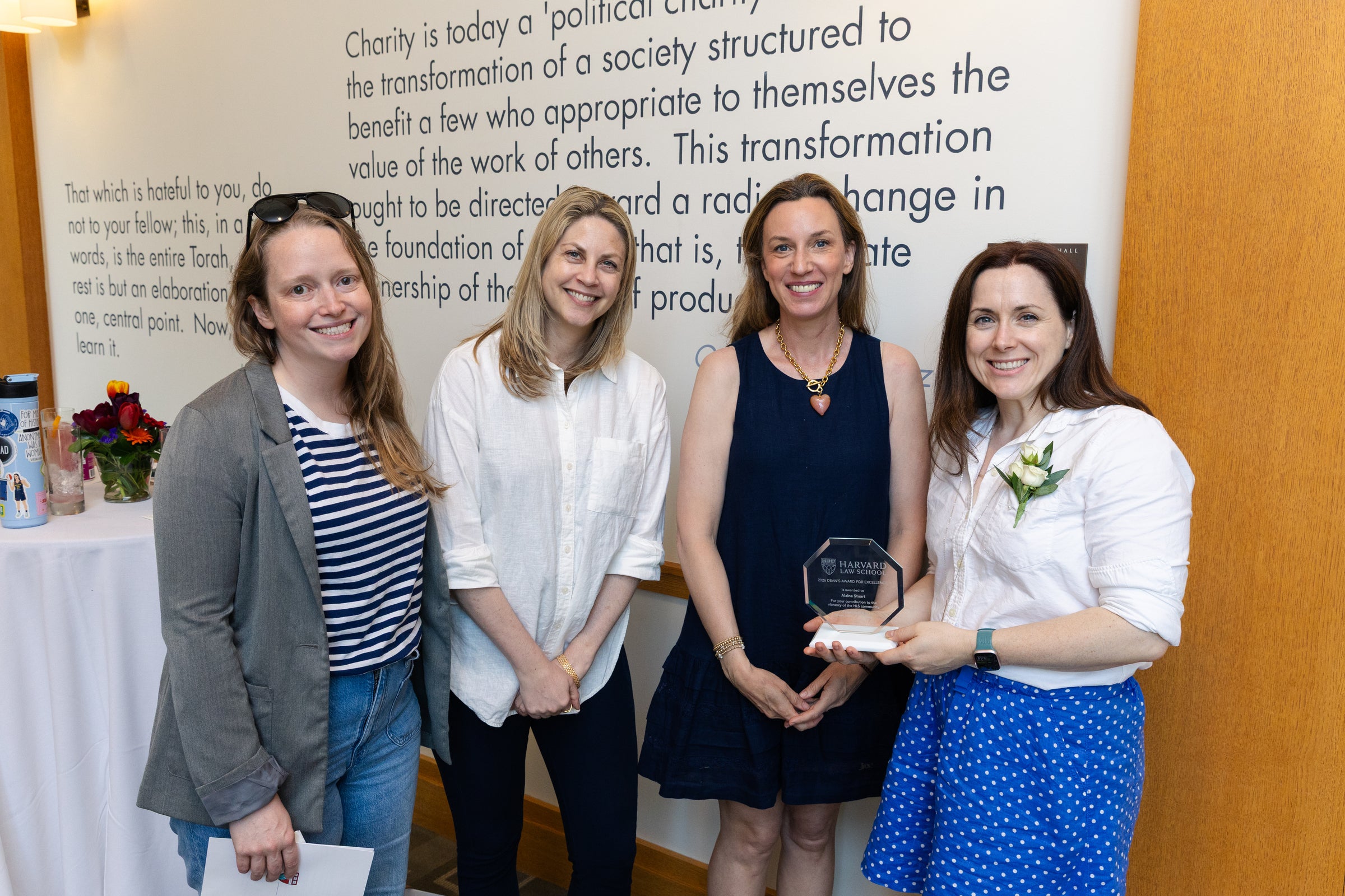 Four individuals pose together at an event, with the person on the right holding an award.