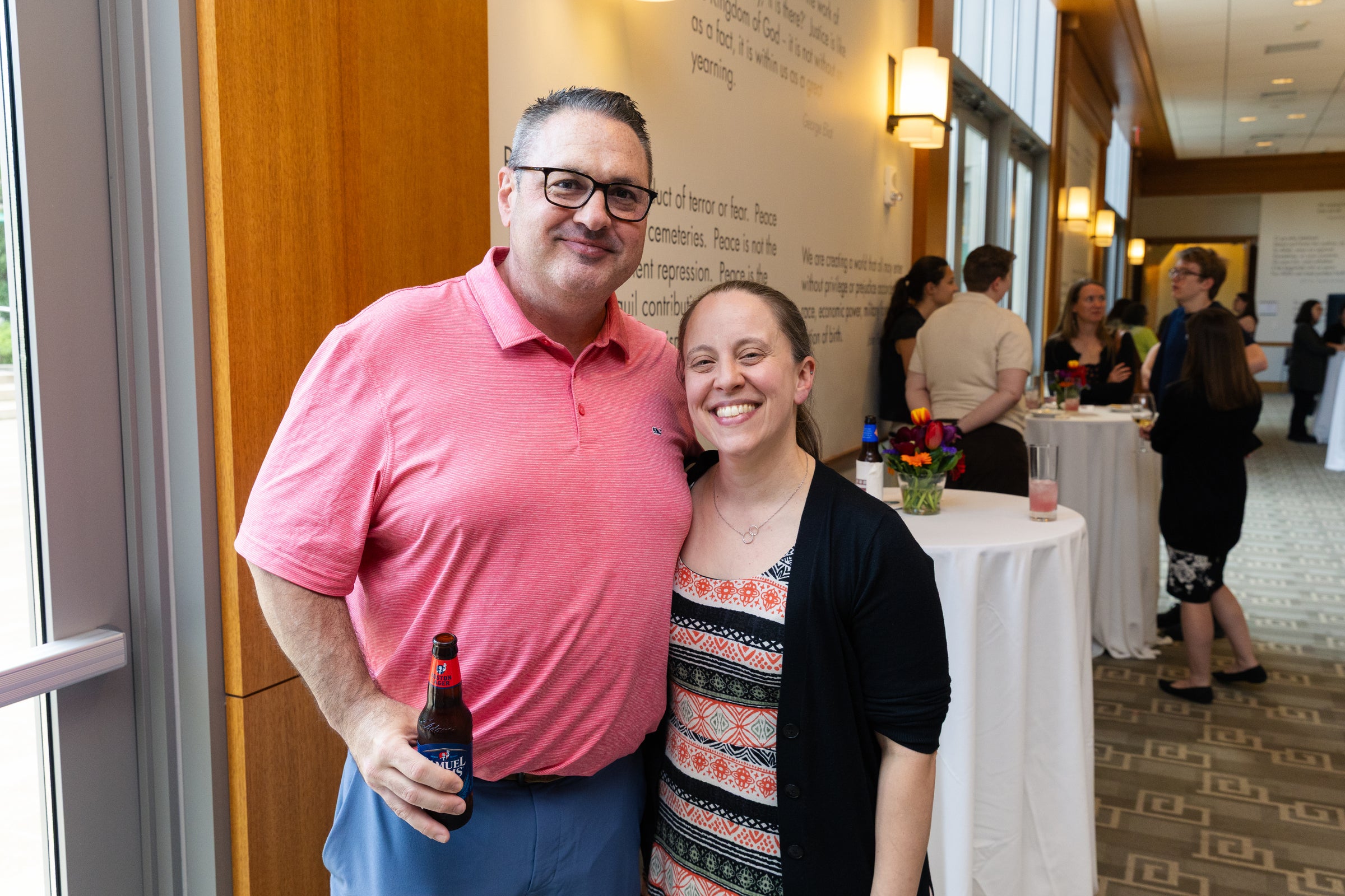 Two people smile for the camera at an indoor event.