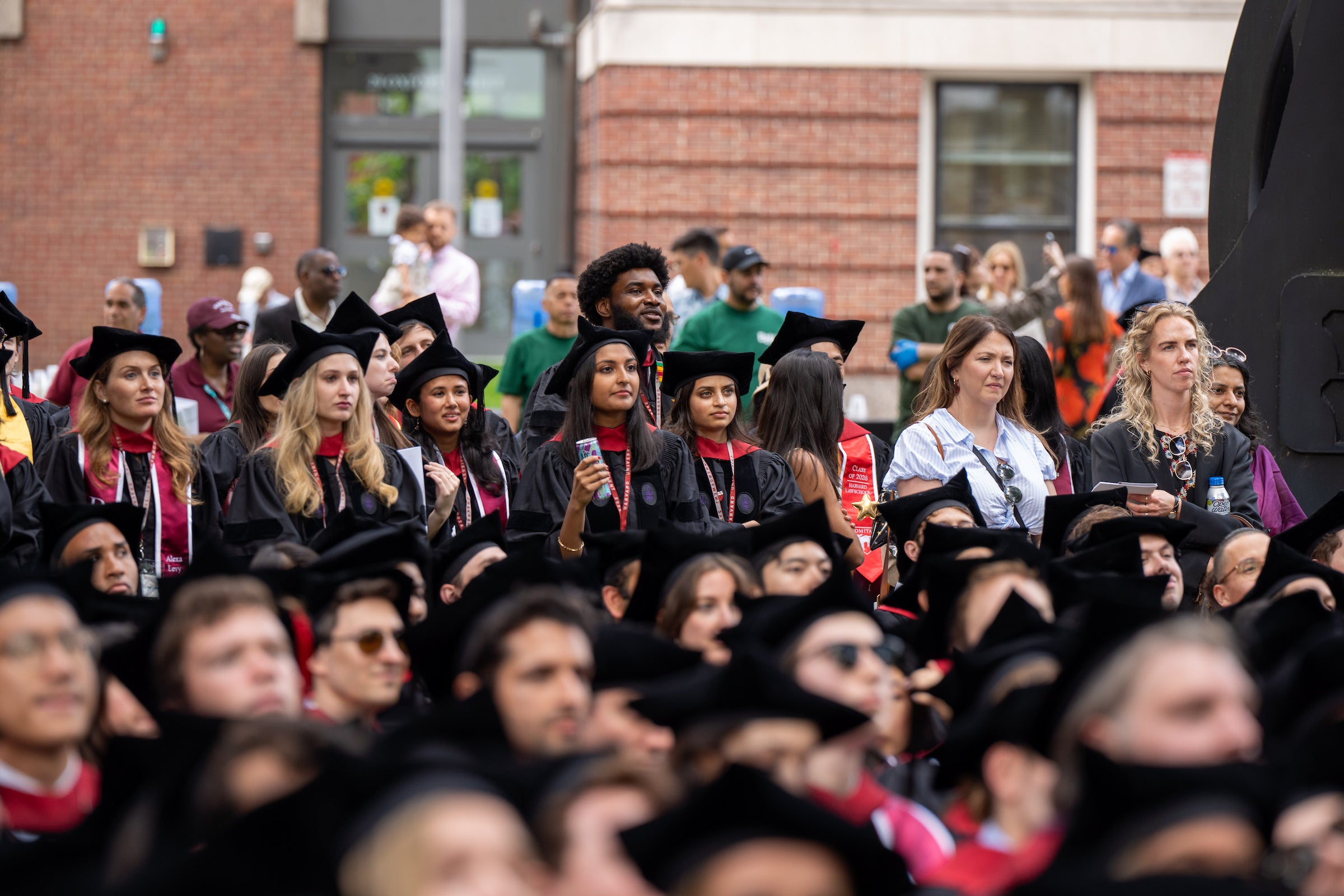 Students in commencement regalia standing behind rows of graduate students sitting.