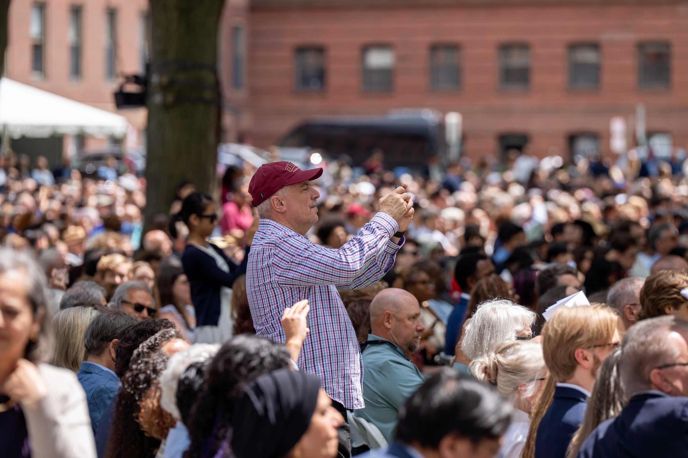 Man standing up in an audience taking a photo.