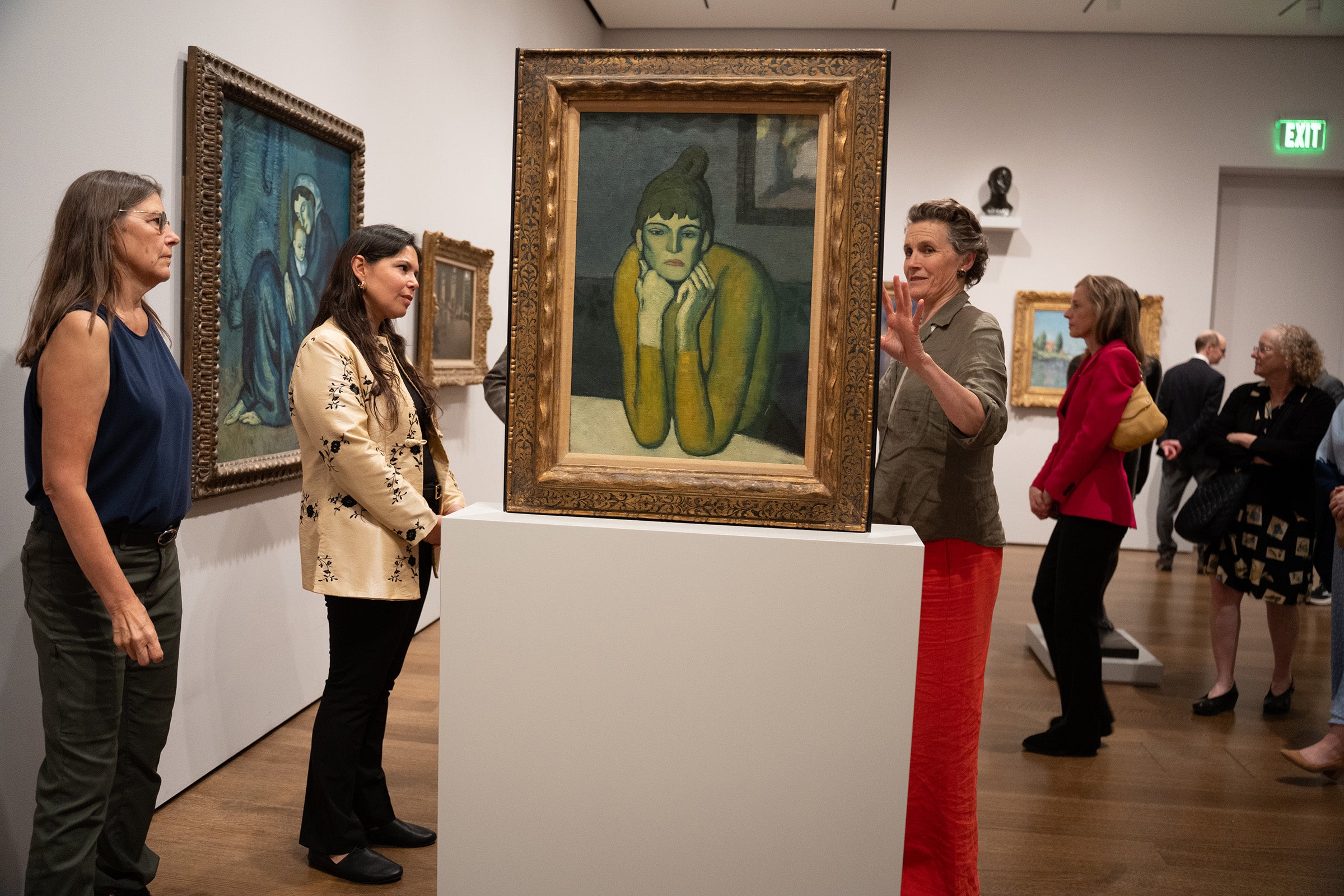 A woman discusses artwork with attendees.