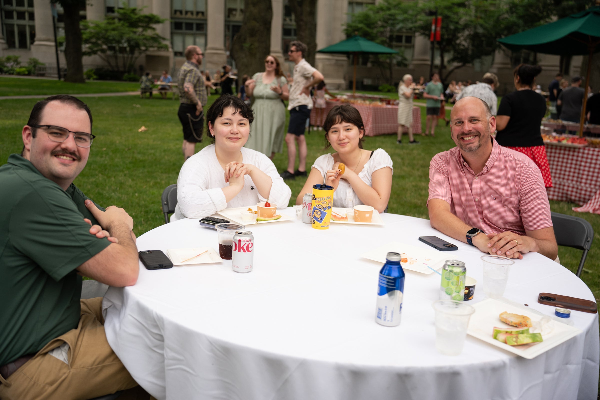 Four people seated at a round table set with food and drinks smile for the camera.
