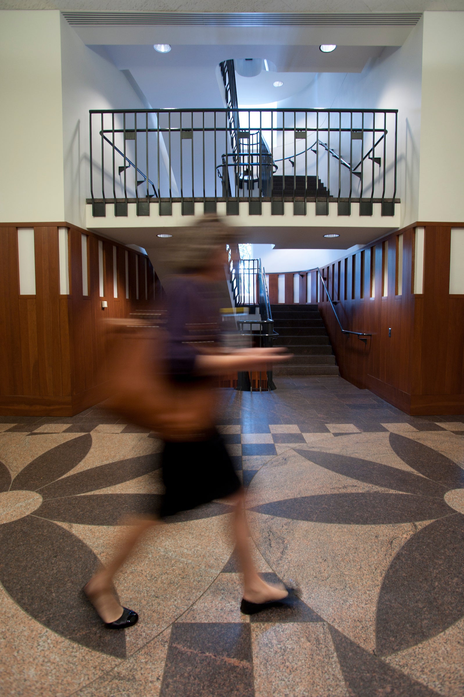 A student walks tthrough and interior foyer of the Hauser Hall.