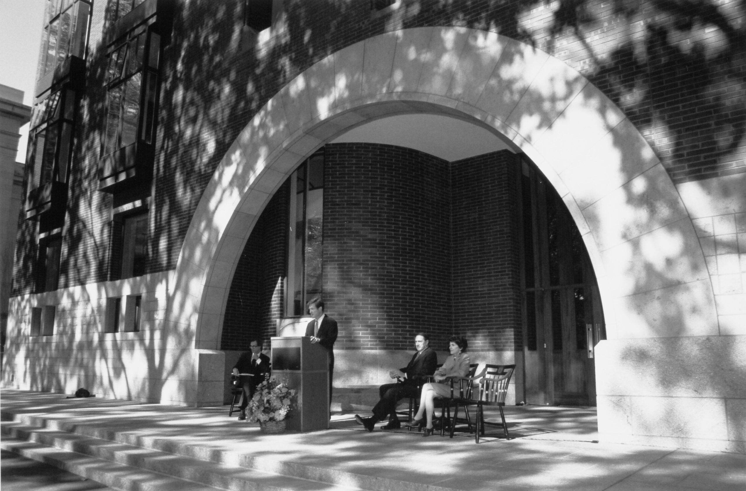 Three people stand near a podium at the front of a building.