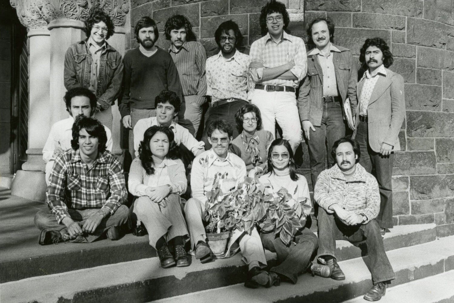 Full-length view of 15 men and women standing and sitting on the steps of Austin Hall