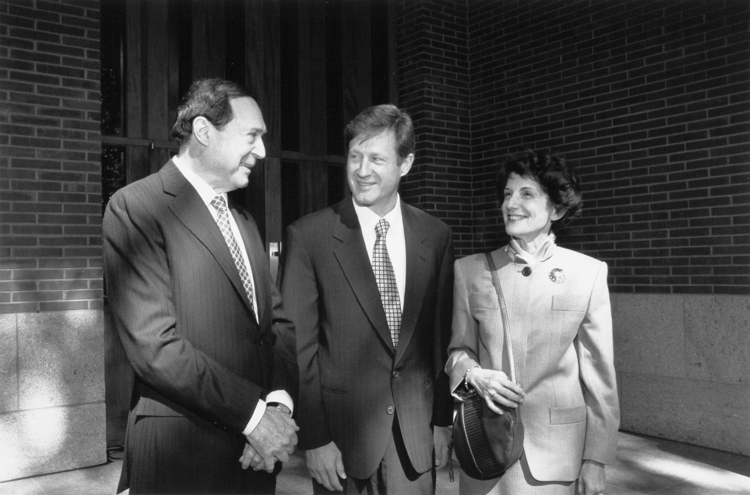 Three people posing in front of a building