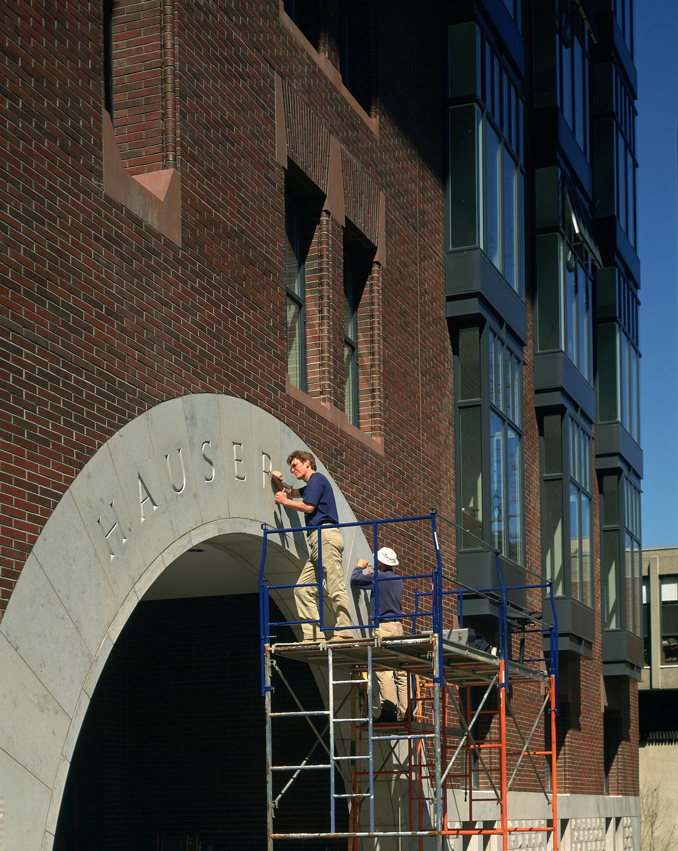 A man carving a name into a marble archway on a building.