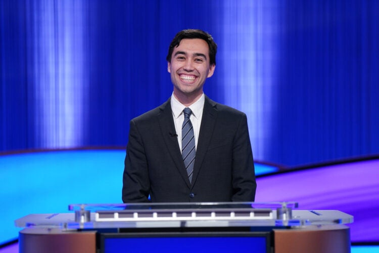 Caleb Groen wearing a suit on the Jeopardy set.