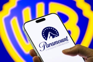 Paramount logo displayed on a phone with the Warner Bros. logo in the background.