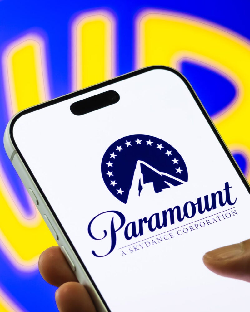 Paramount logo displayed on a phone with the Warner Bros. logo in the background.