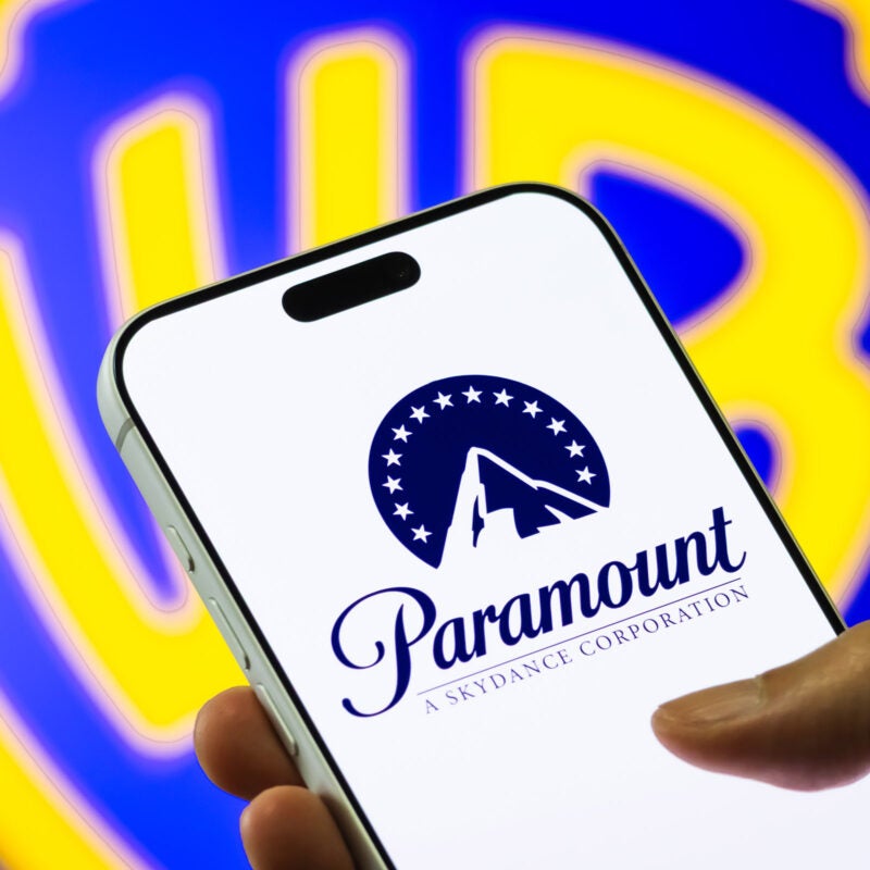 Paramount logo displayed on a phone with the Warner Bros. logo in the background.