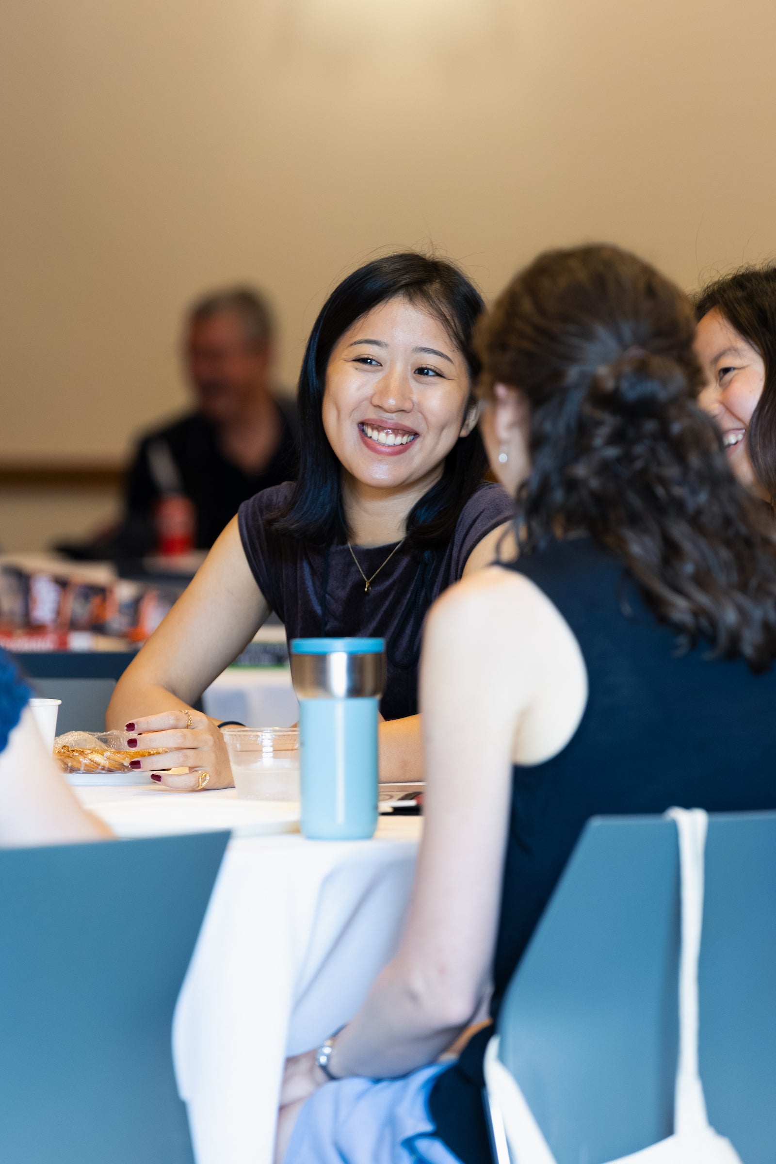 A group of students are laughing and chatting together at a table.