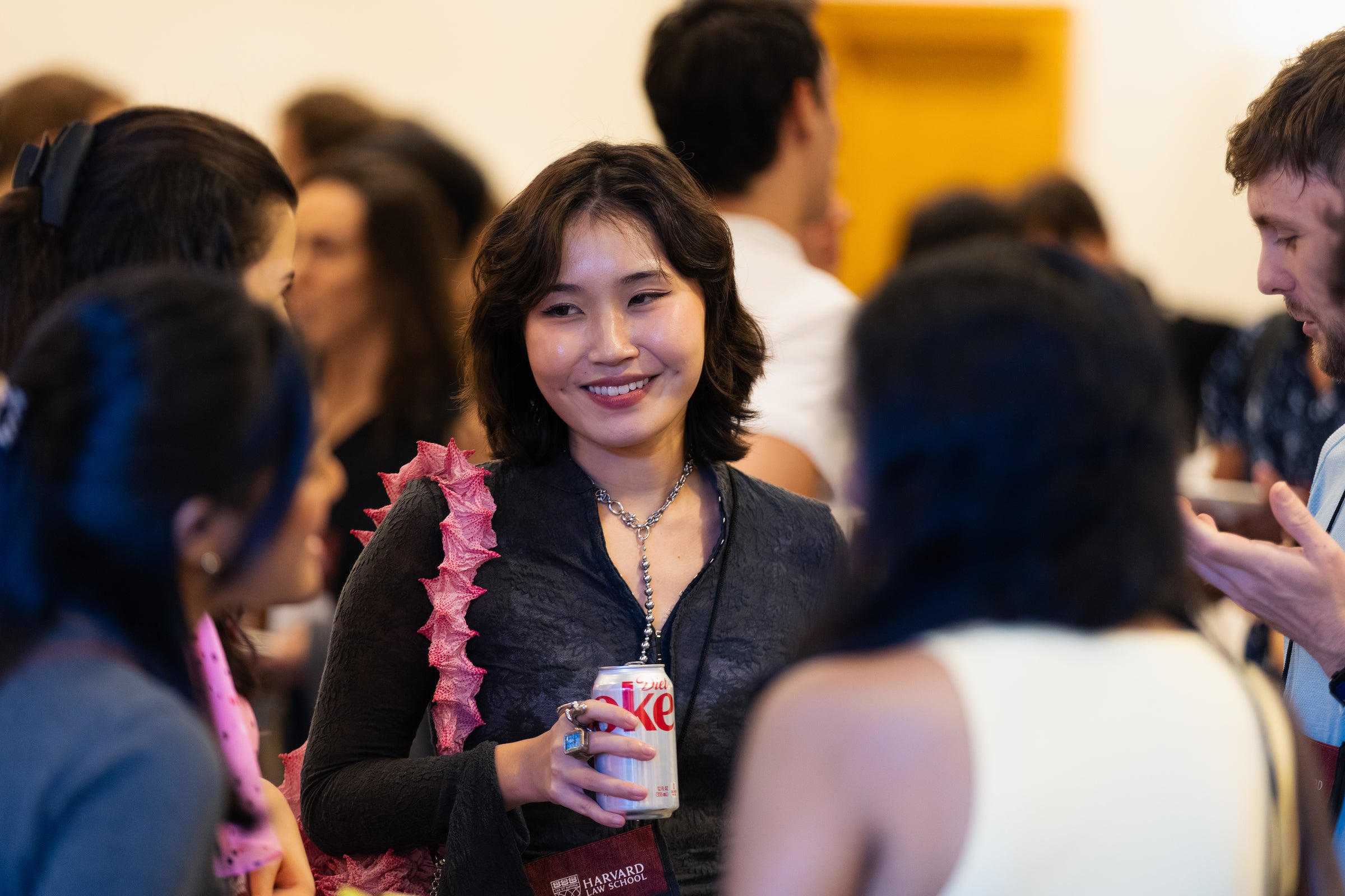 A student holds a can of soda while smiling and engaging in conversation.