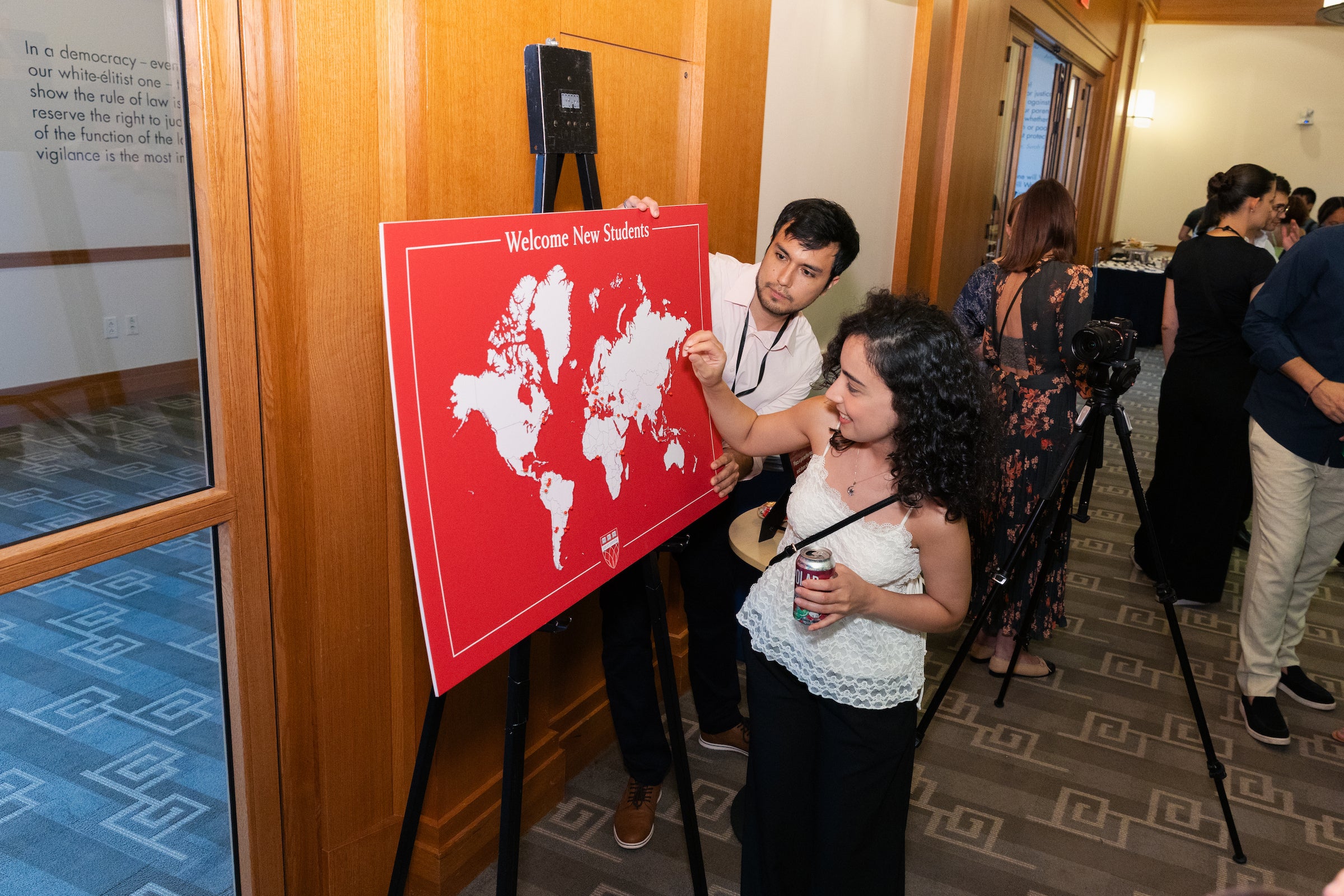 A student puts a pin in a red world map display at an event welcoming new students.