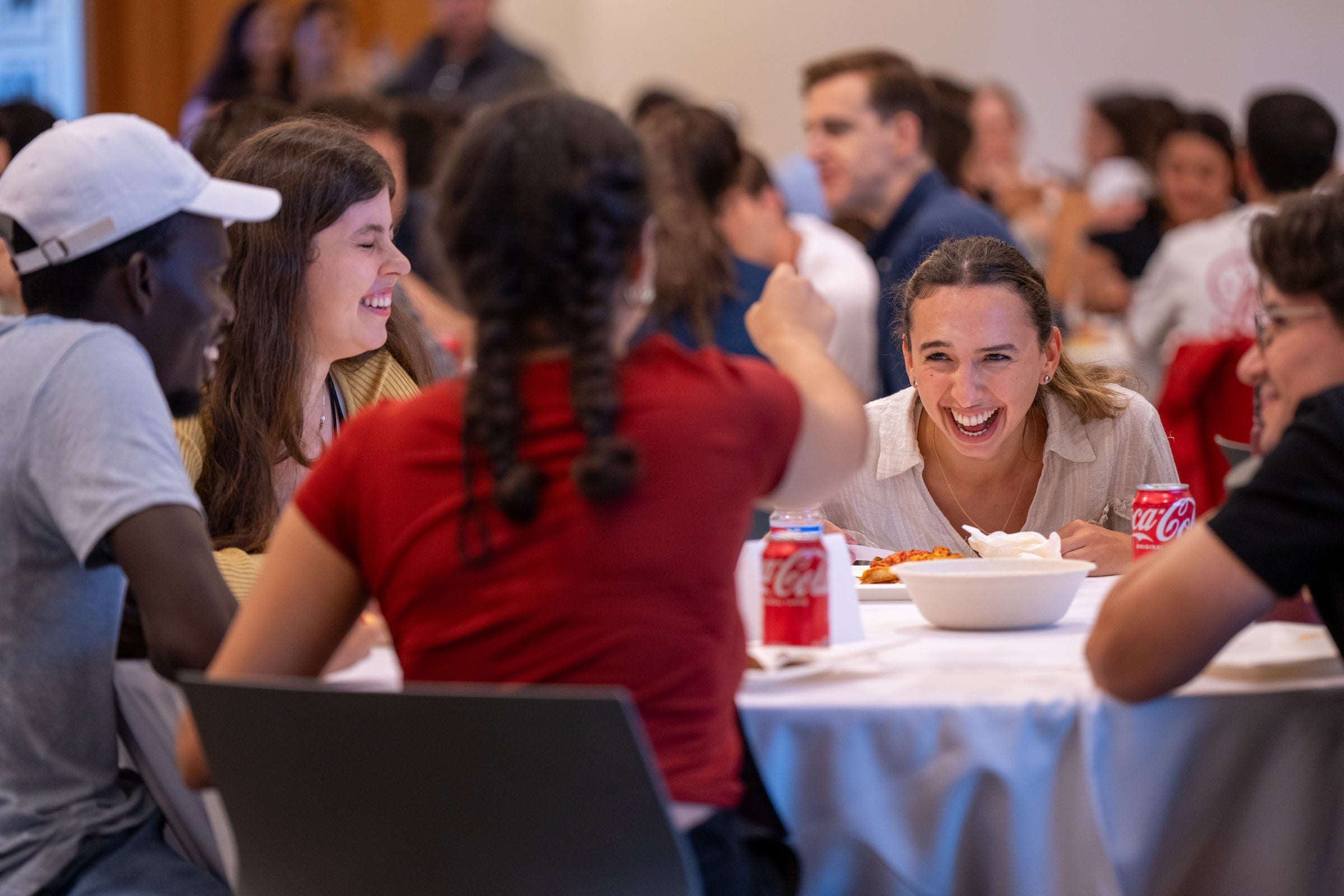 A group of people laugh and socialize together at a round dining table.