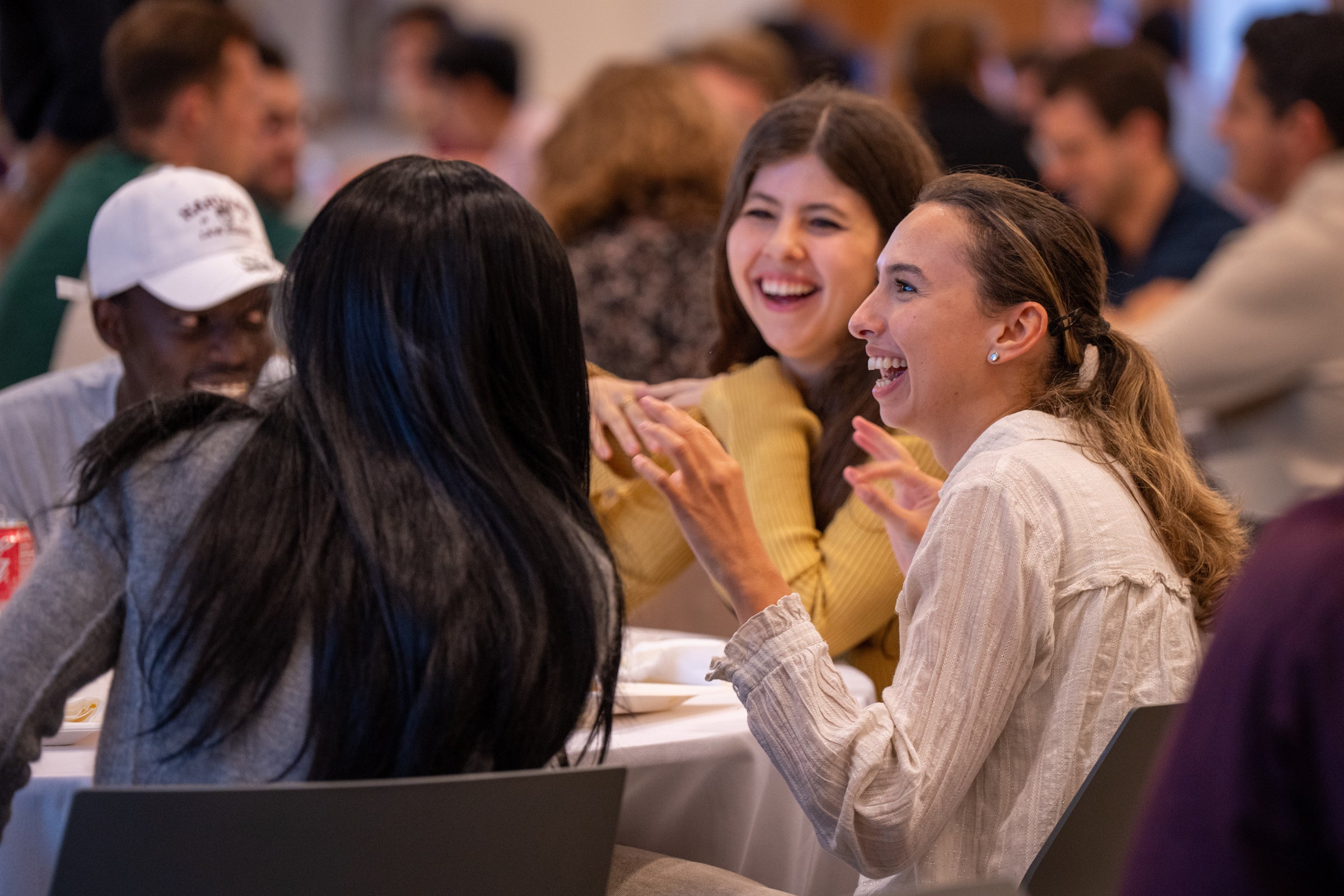 Students laugh around a table at a social event.