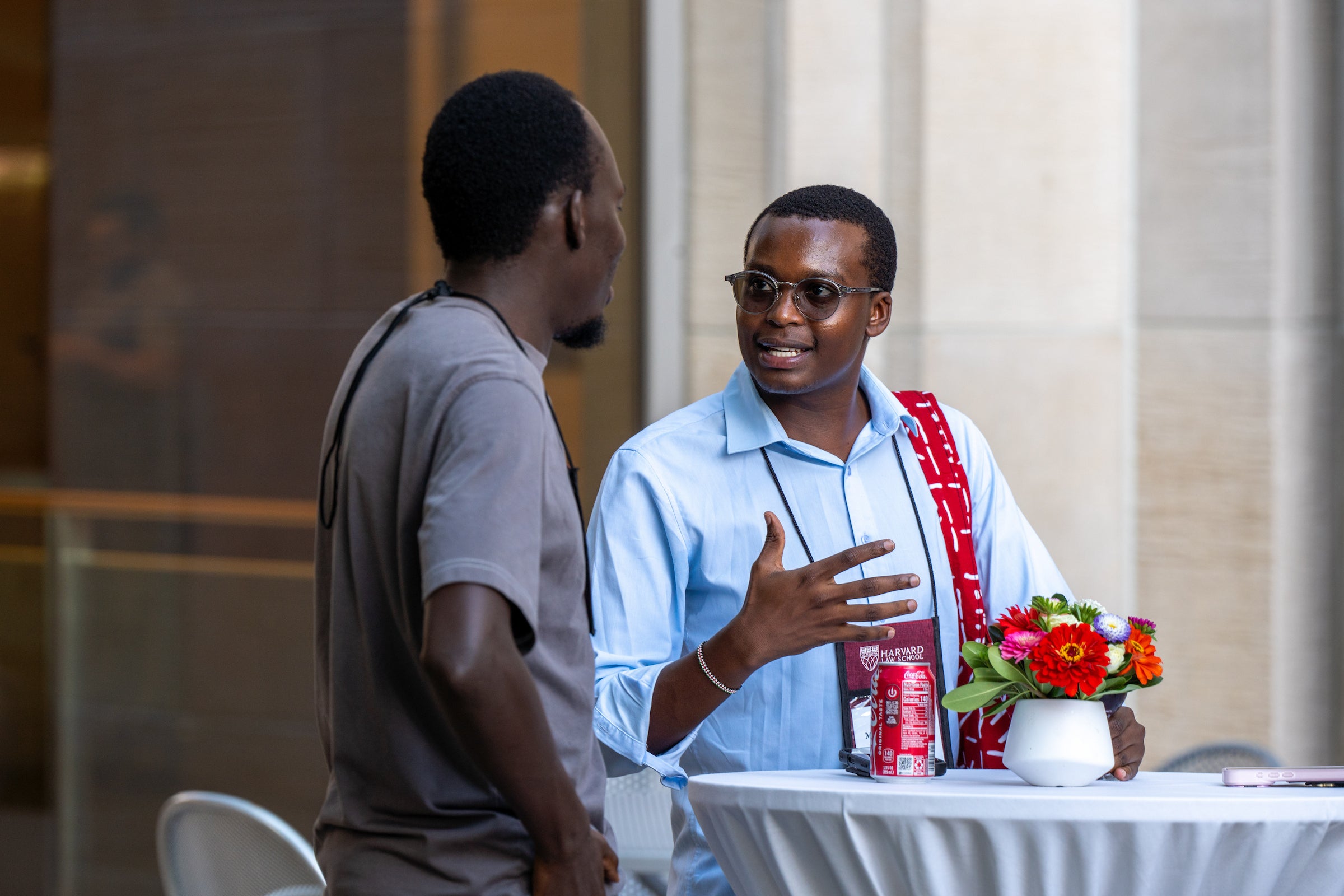 Two students engage in conversation at an outdoor table adorned with a small floral arrangement.