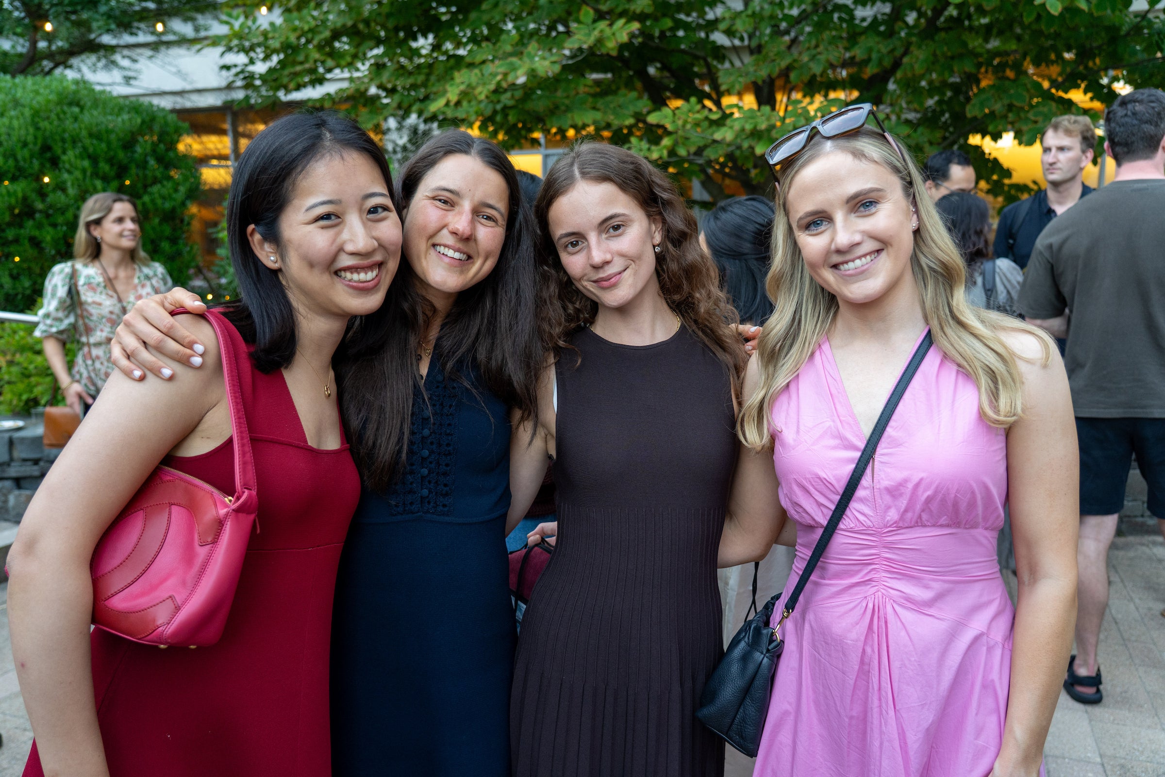A group of four students smile for the camera with their arms around each other at an outdoor event.