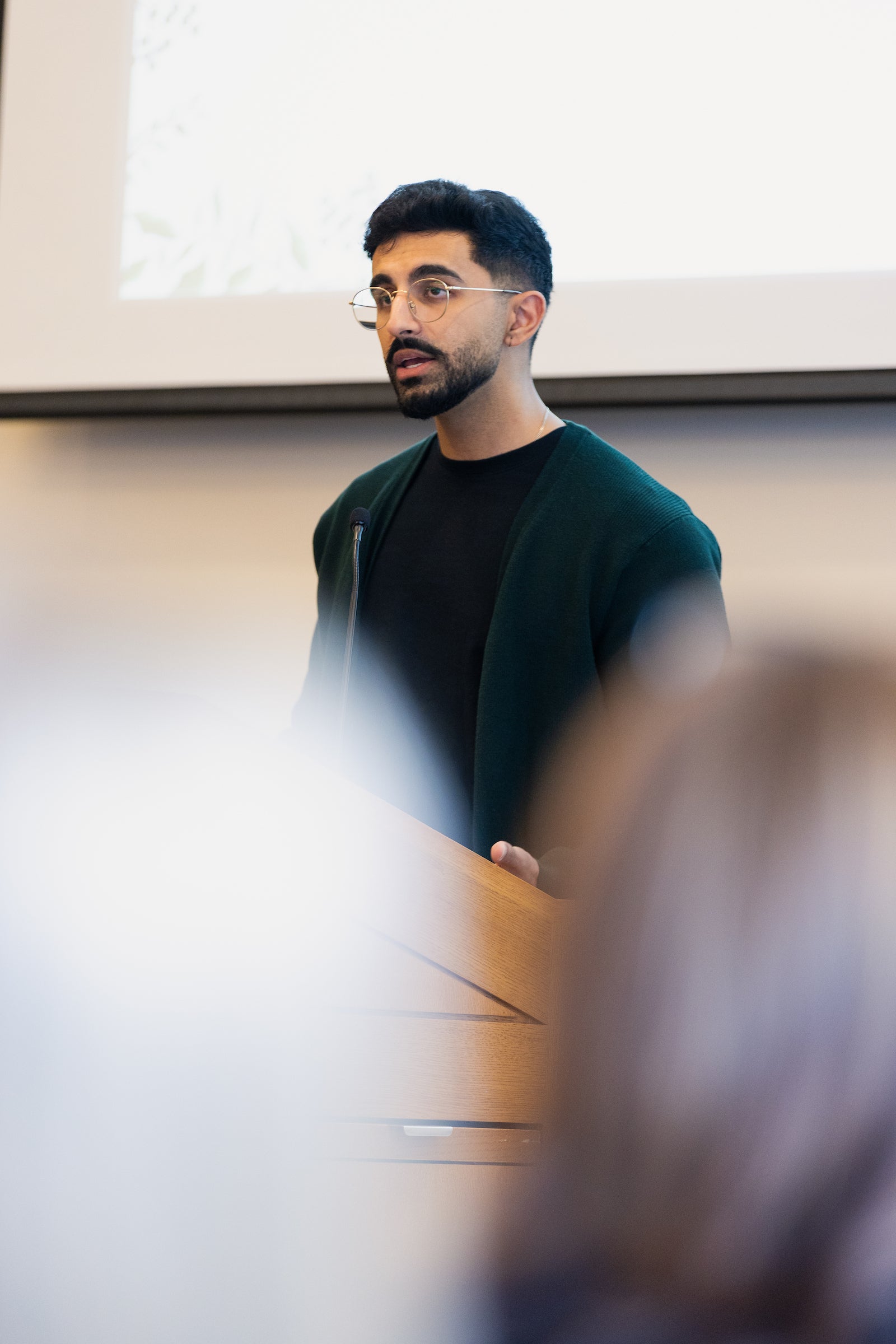 An individual speaks to an audience from a podium.