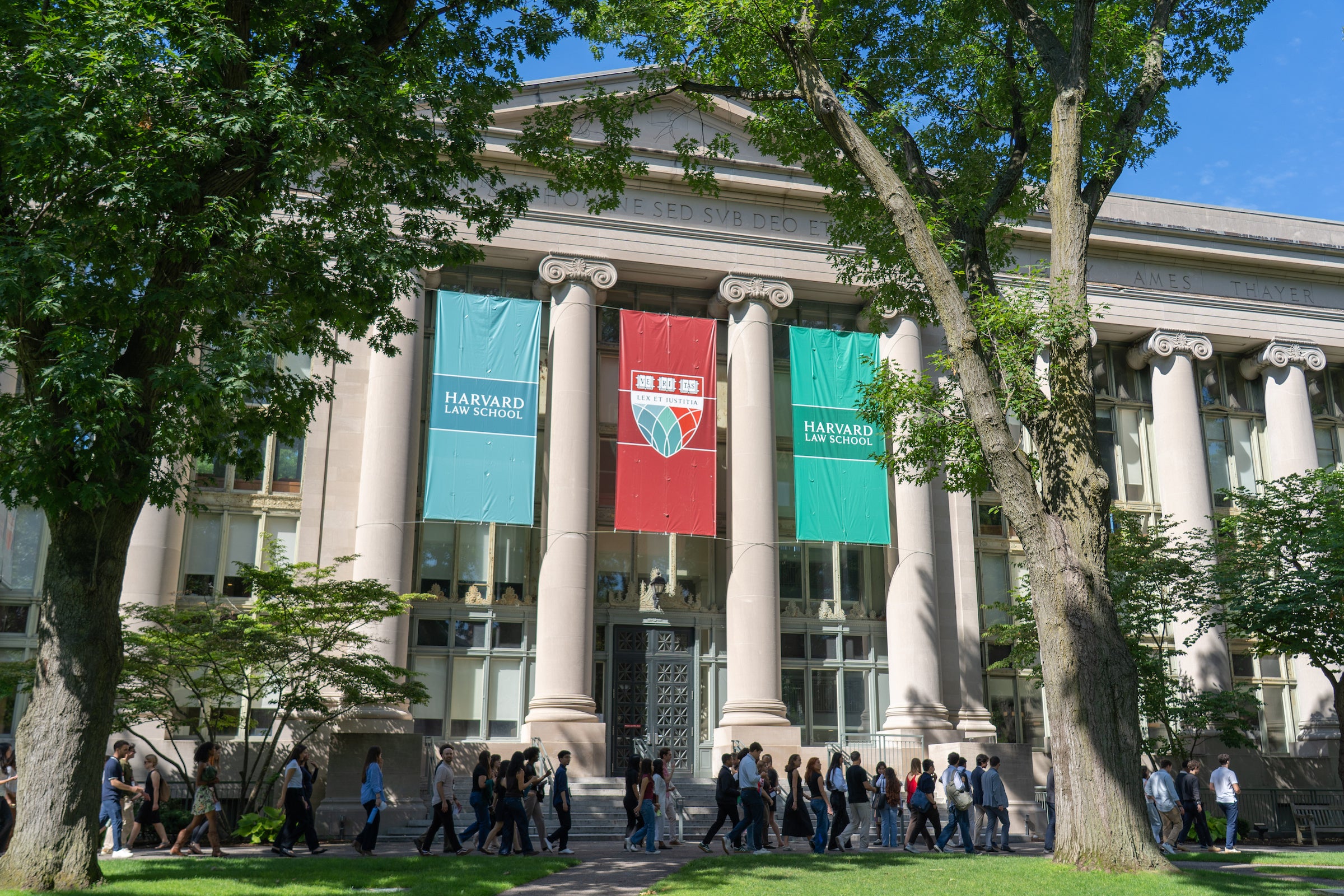 Students walk in front of Langdell Hall on a sunny day.