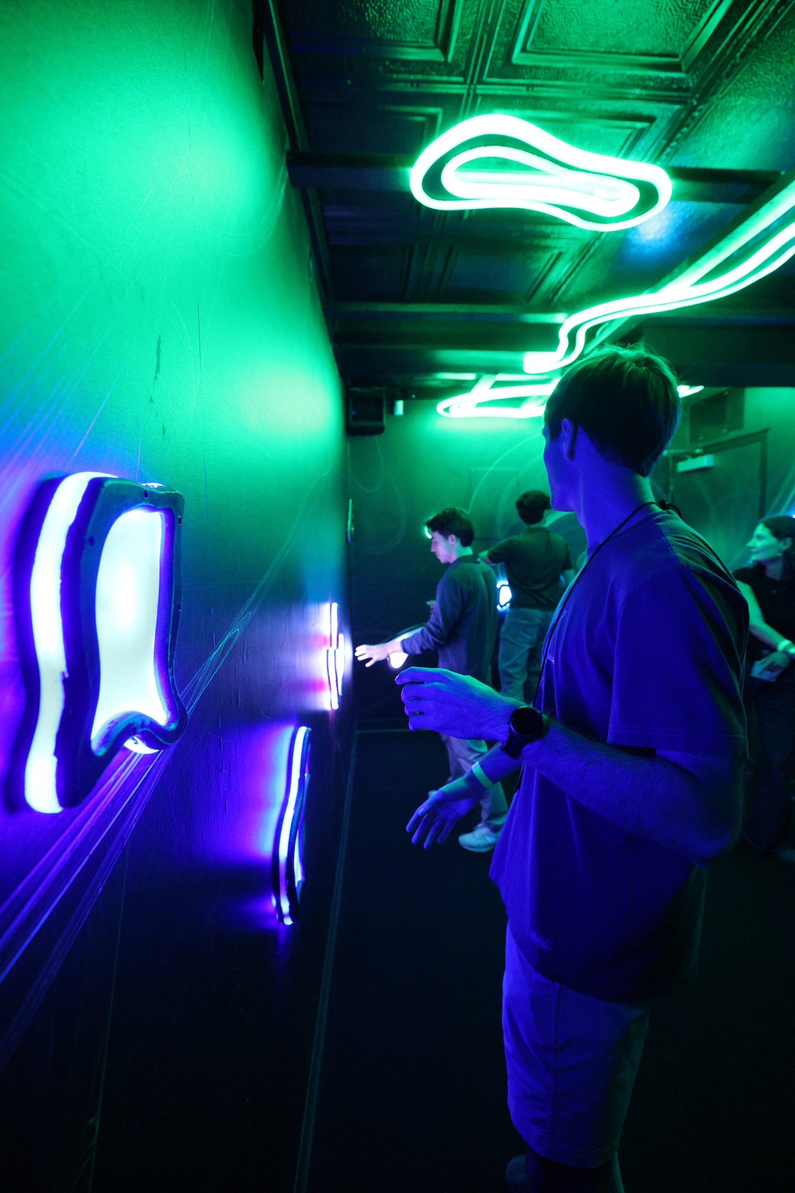 Students participate in a dark escape room with bright green and blue neon lights.