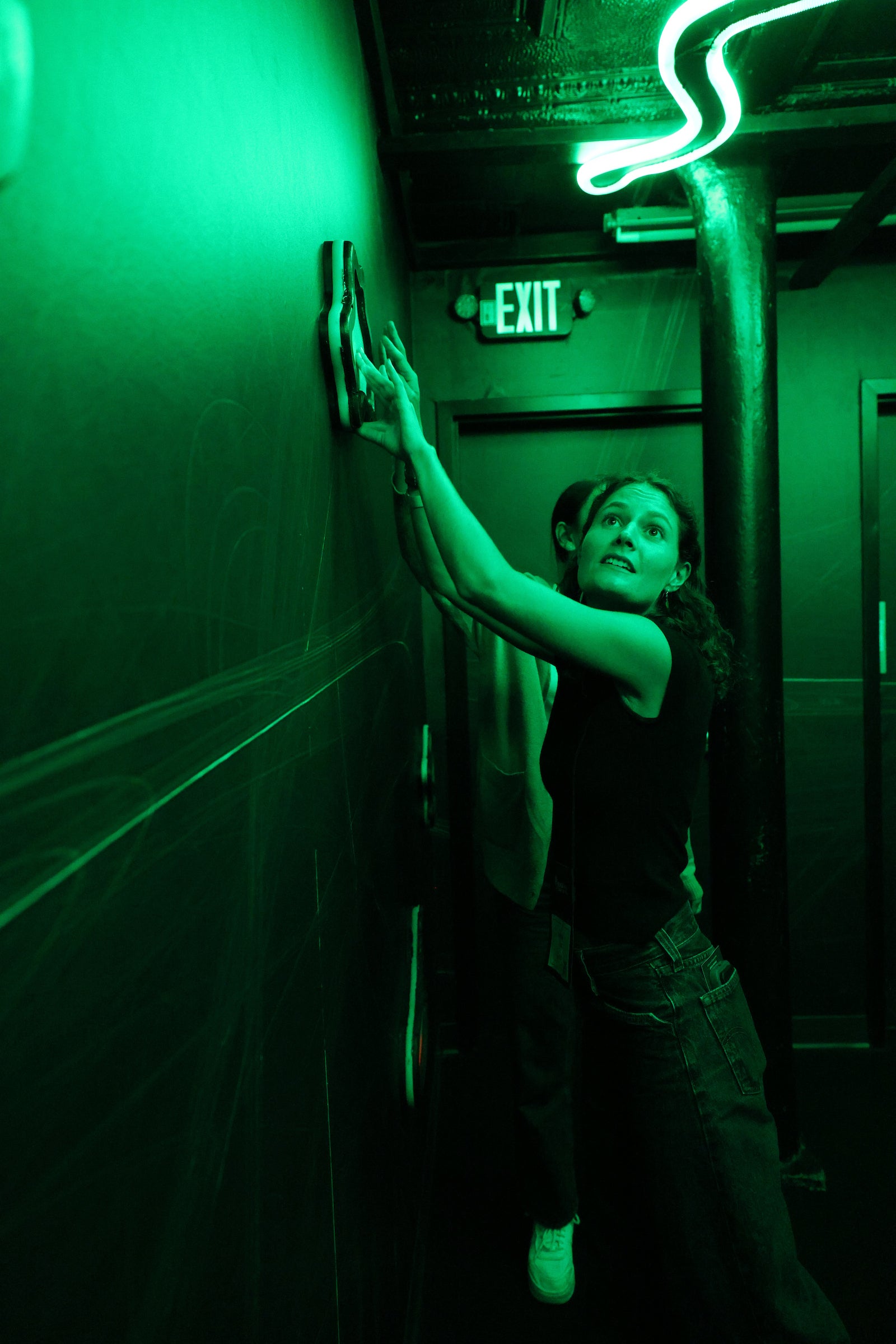 Students participate in a dark escape room with bright green neon lights.