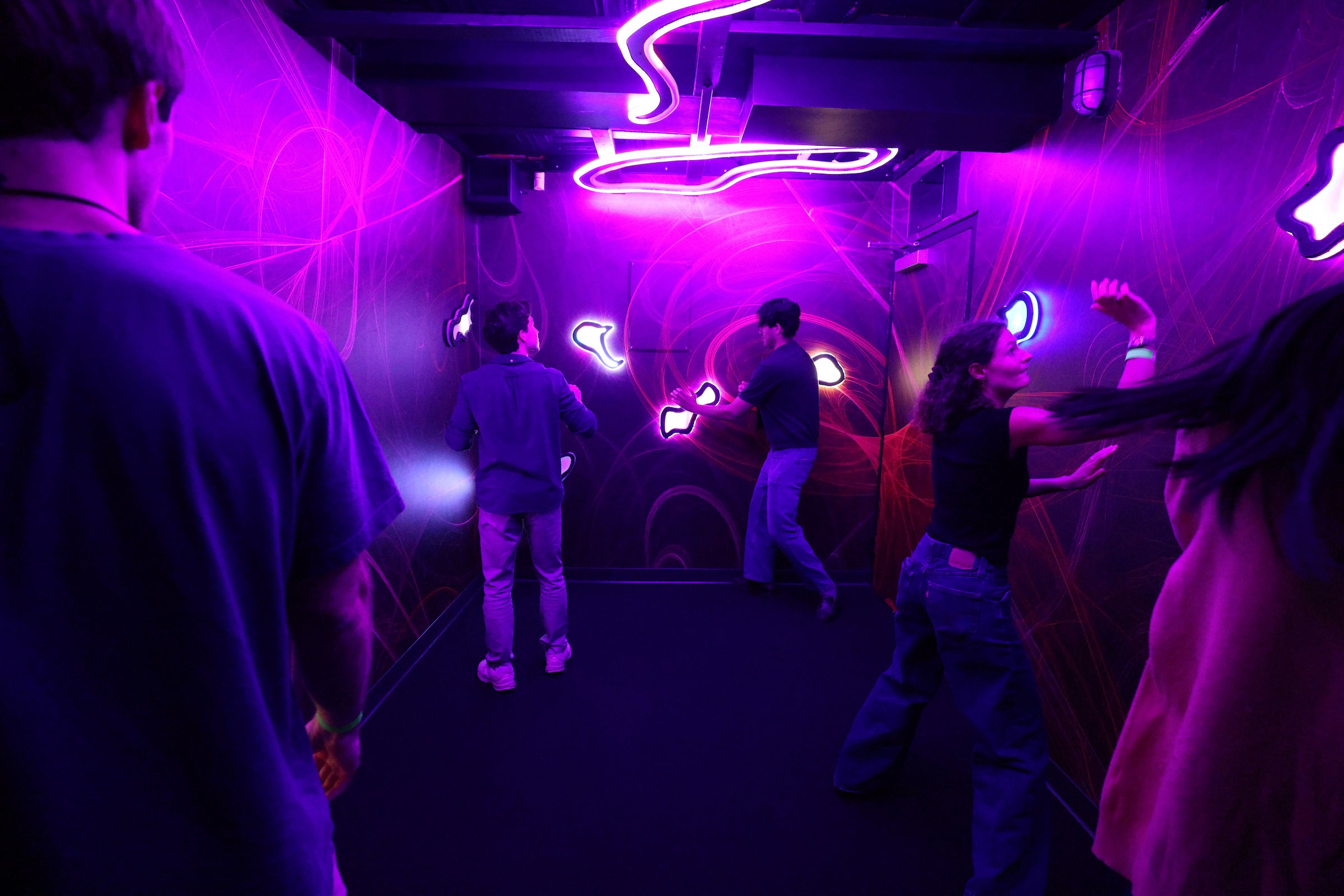 Students participate in a dark escape room with bright purple neon lights.
