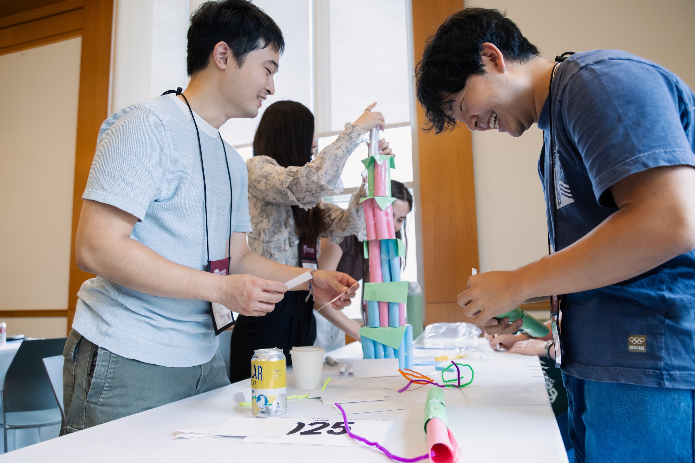 Students laugh while building colorful paper structures together.