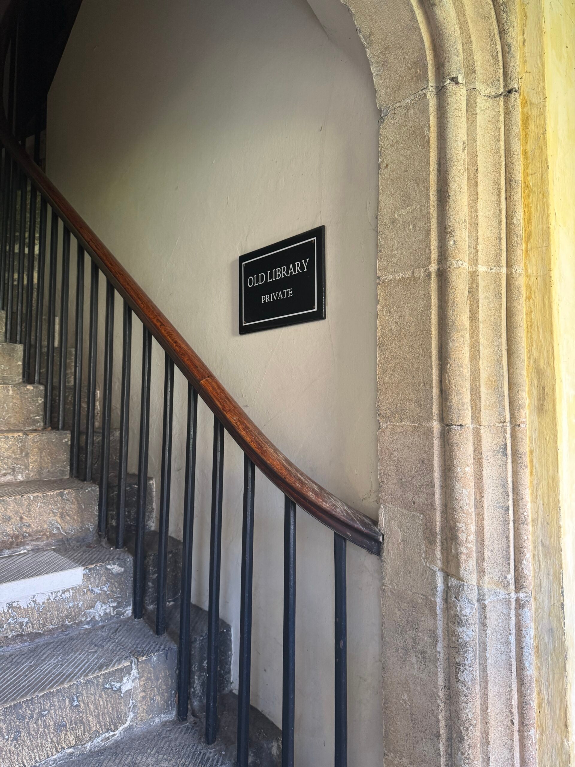 Arched doorway leading to a stairway with a plaque on the wall.