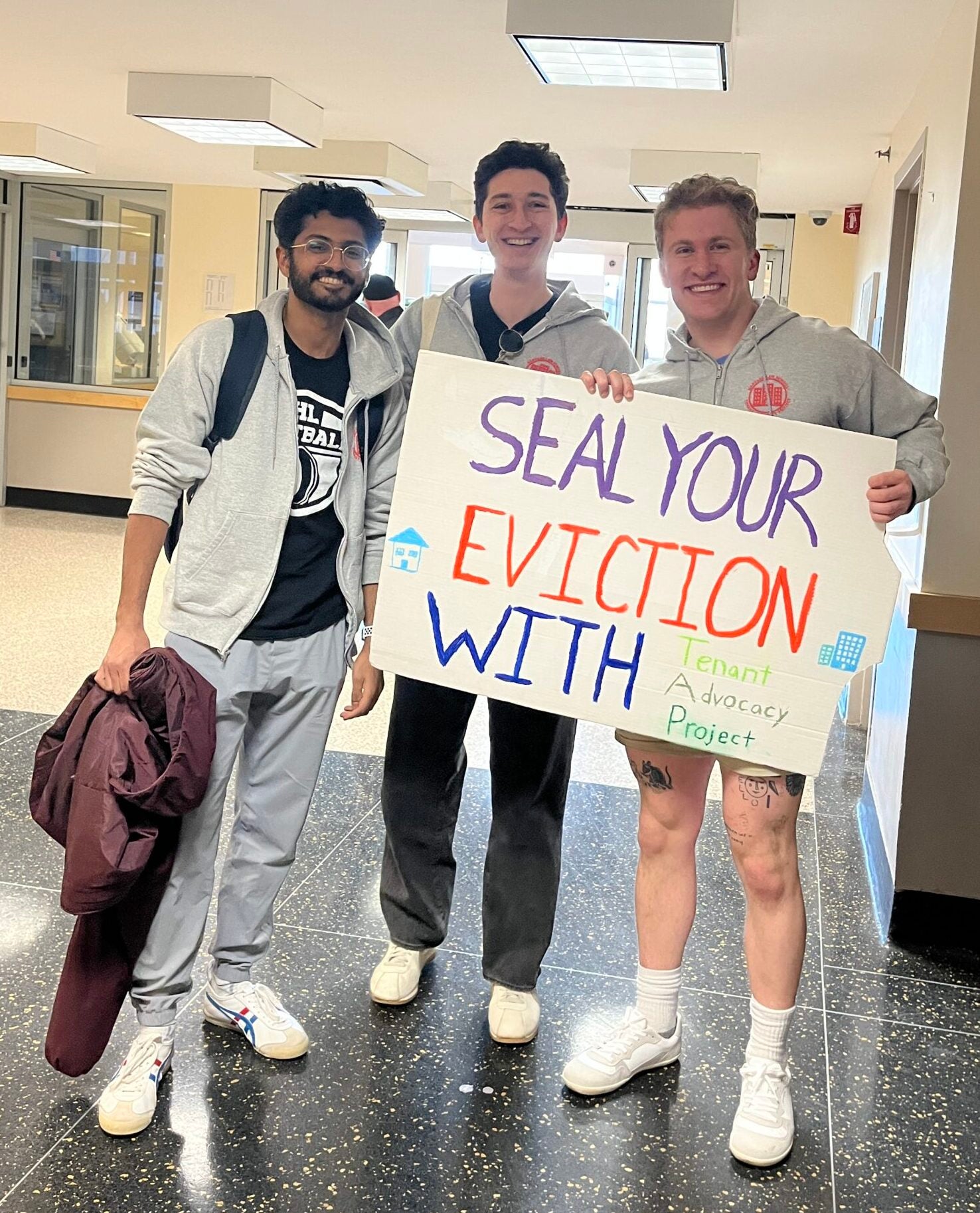 students stand with a sign saying 'Seal Your Eviction with TAP'